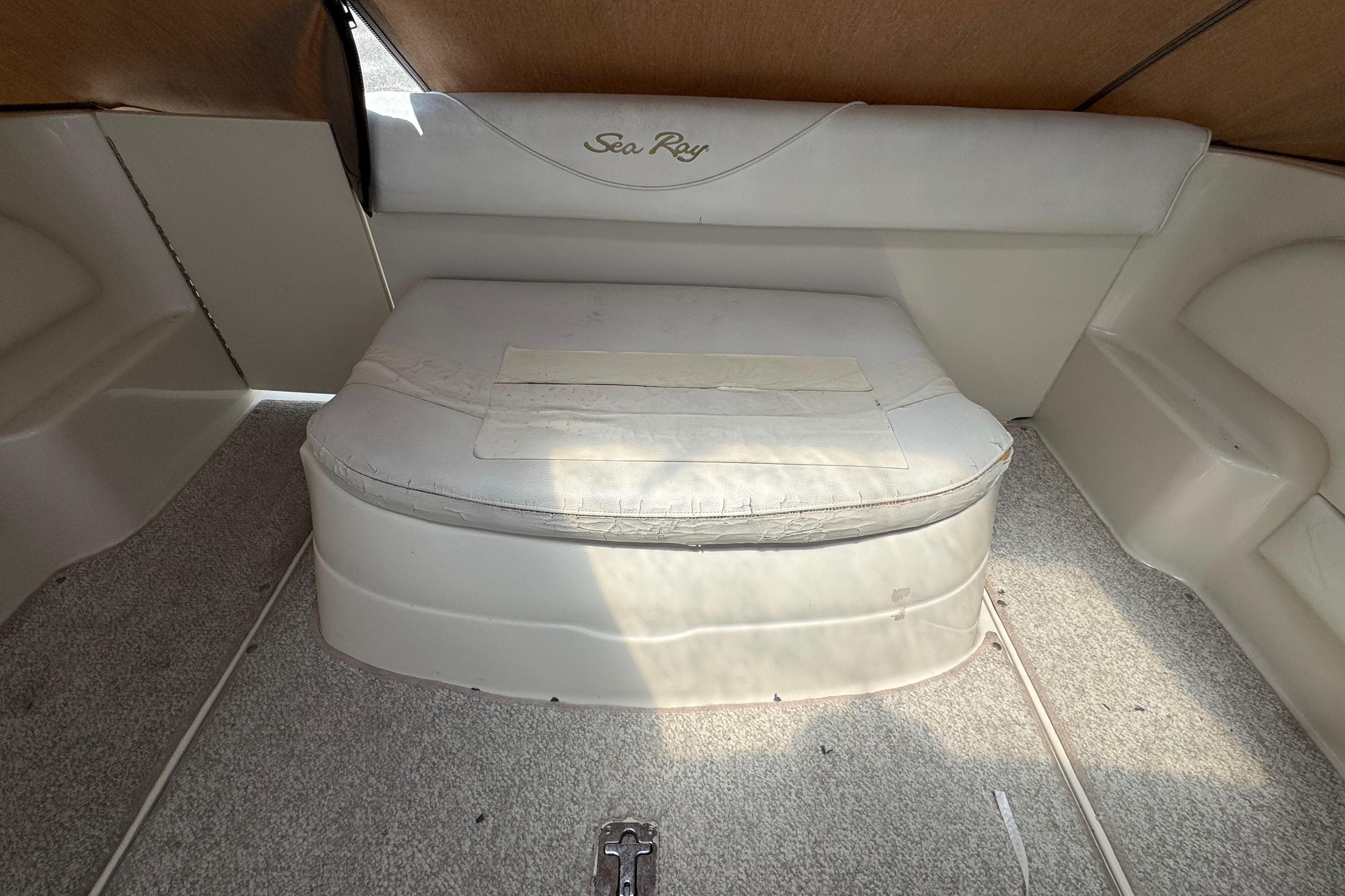 2001 Sea Ray 245 Weekender cabin interior with cushioned seating and carpeted flooring.