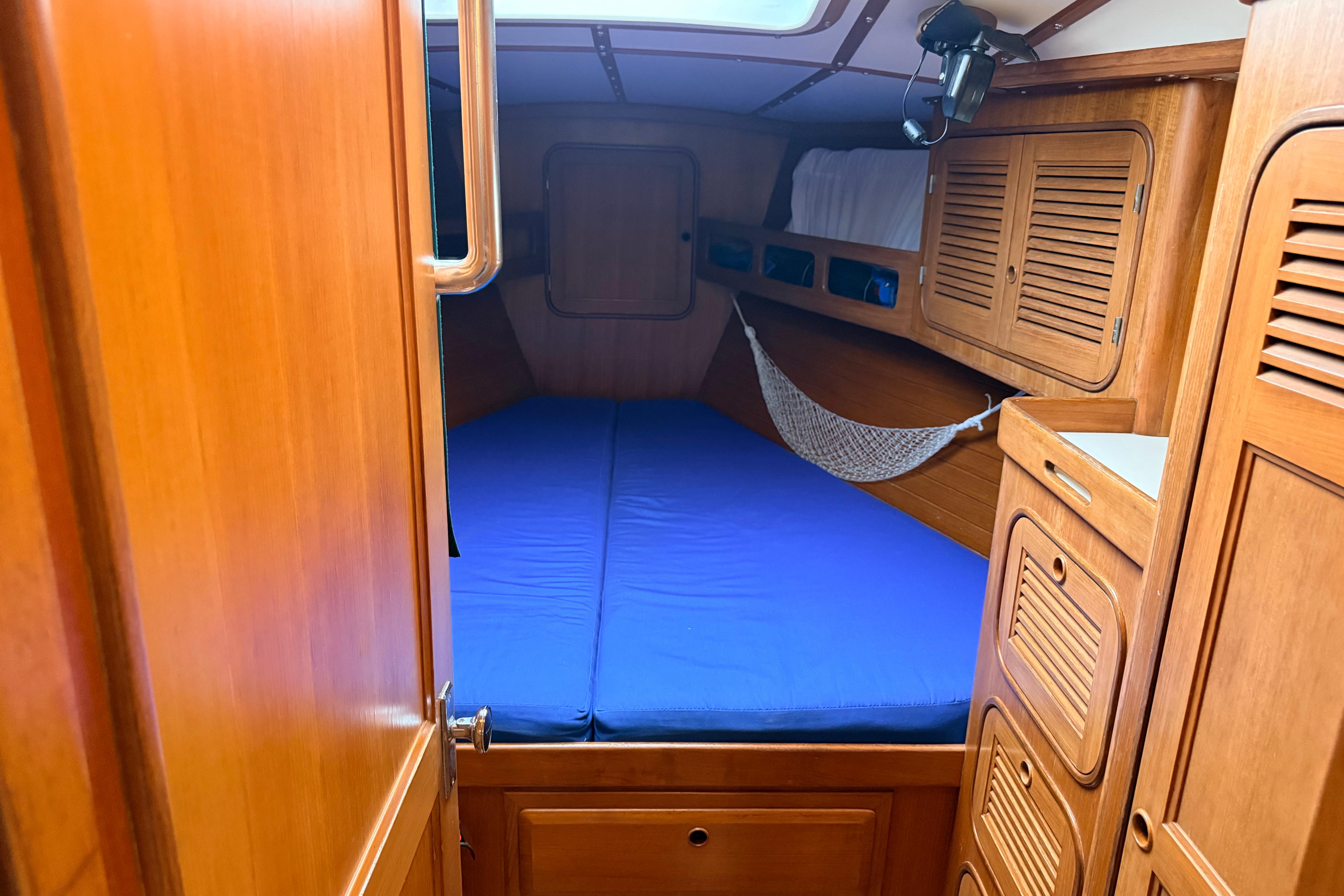 Cozy cabin interior of 1987 Norseman 400 sailboat with wooden finish and blue bedding.