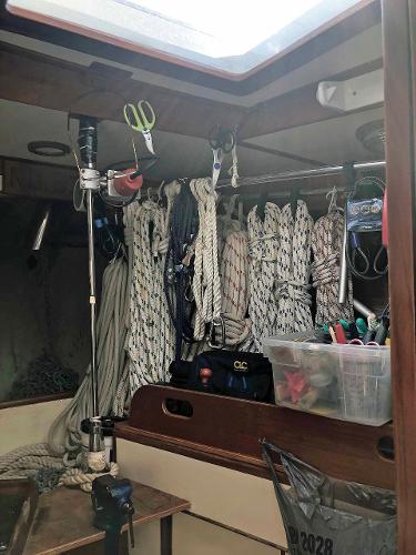 Interior of a sailboat with ropes and tools hanging on the wall.