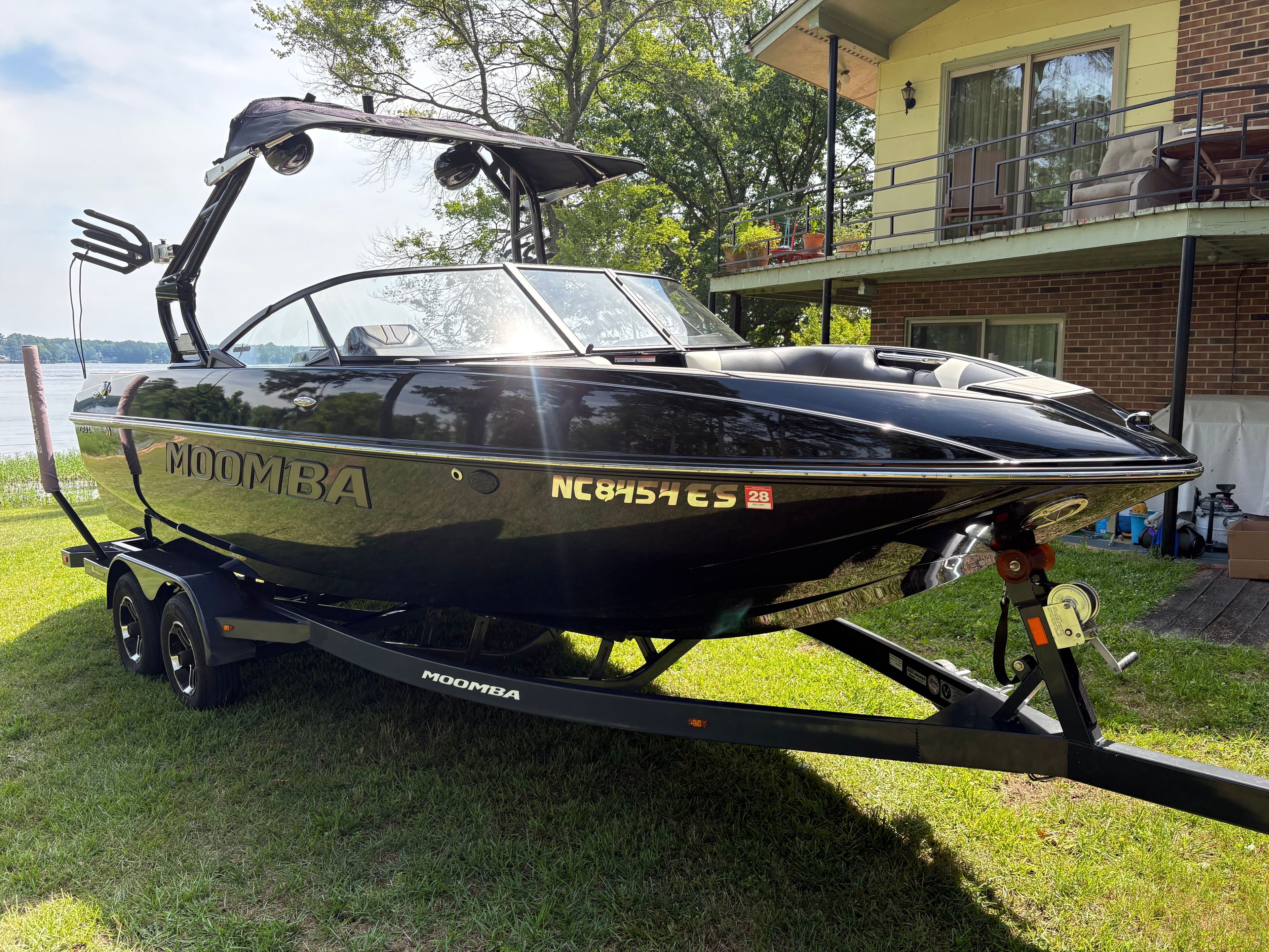 Black 2021 Moomba Craz boat on trailer in front of house.
