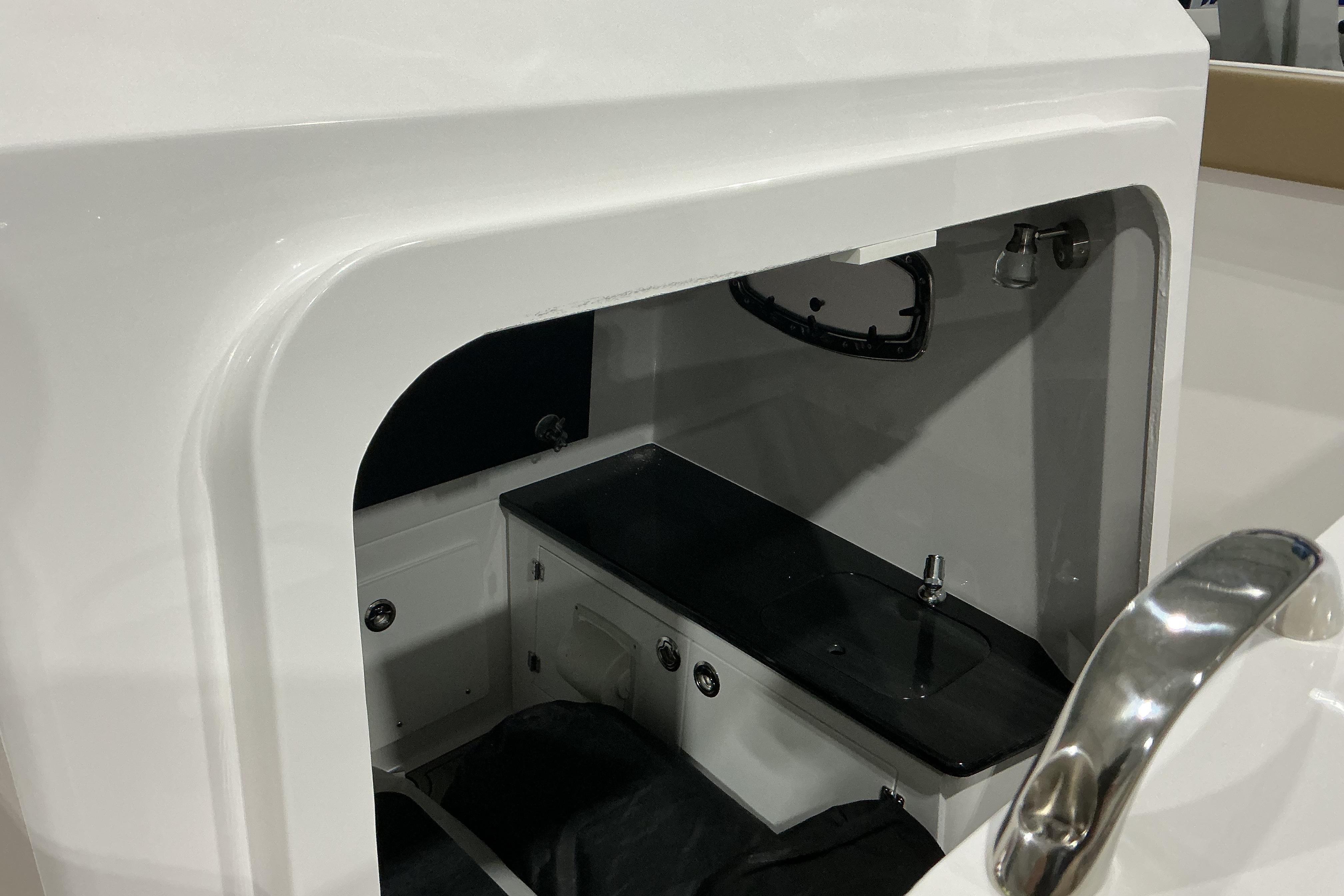 Interior view of 2026 Monterey Elite 25 OB boat cabin with sink and storage.