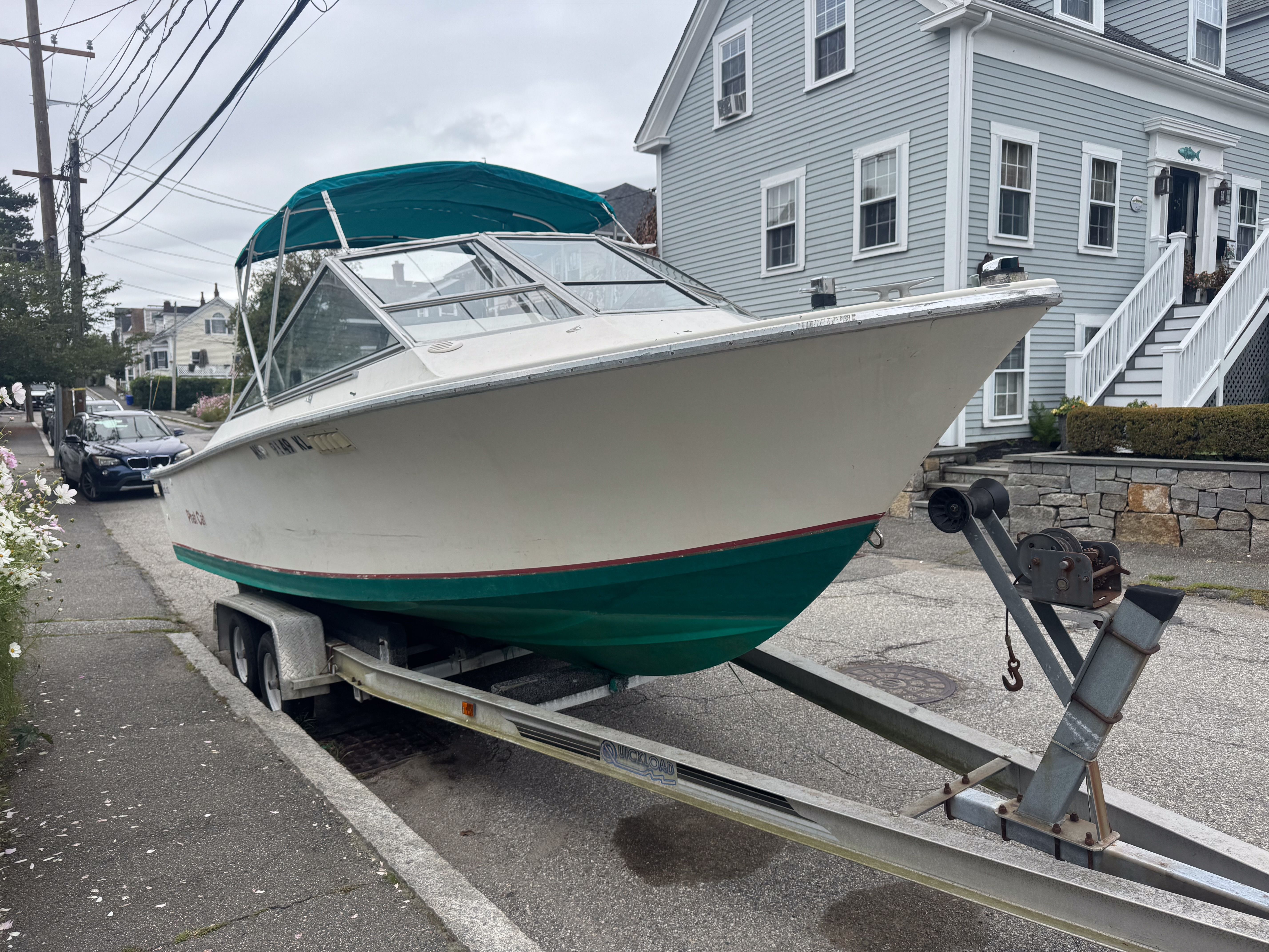 1973 SeaCraft TSUNAMI boat on trailer parked in front of house.