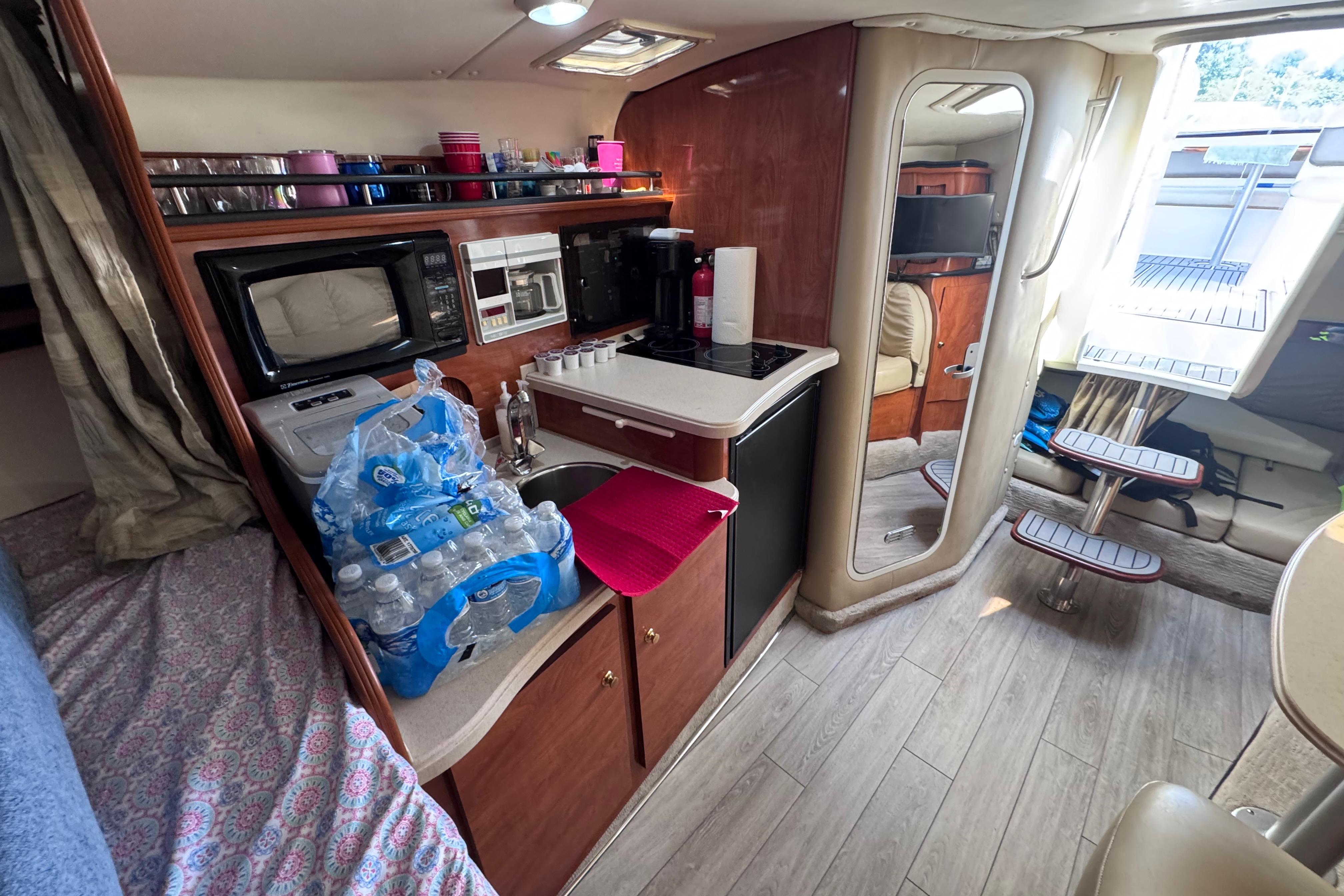 2003 Rinker Fiesta Vee 312 cabin interior with kitchenette, microwave, and seating area.