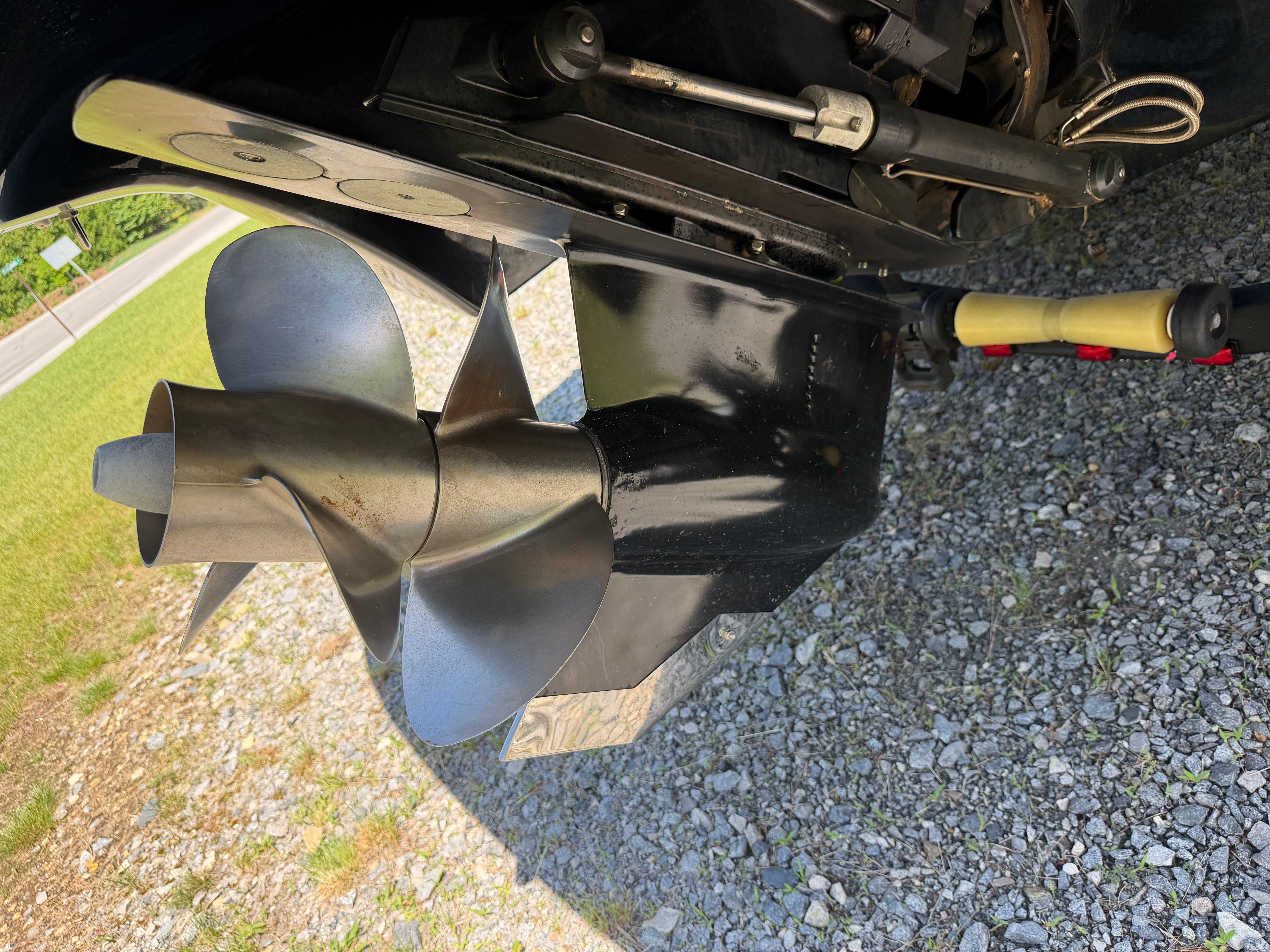Close-up of a boat propeller on a gravel surface.