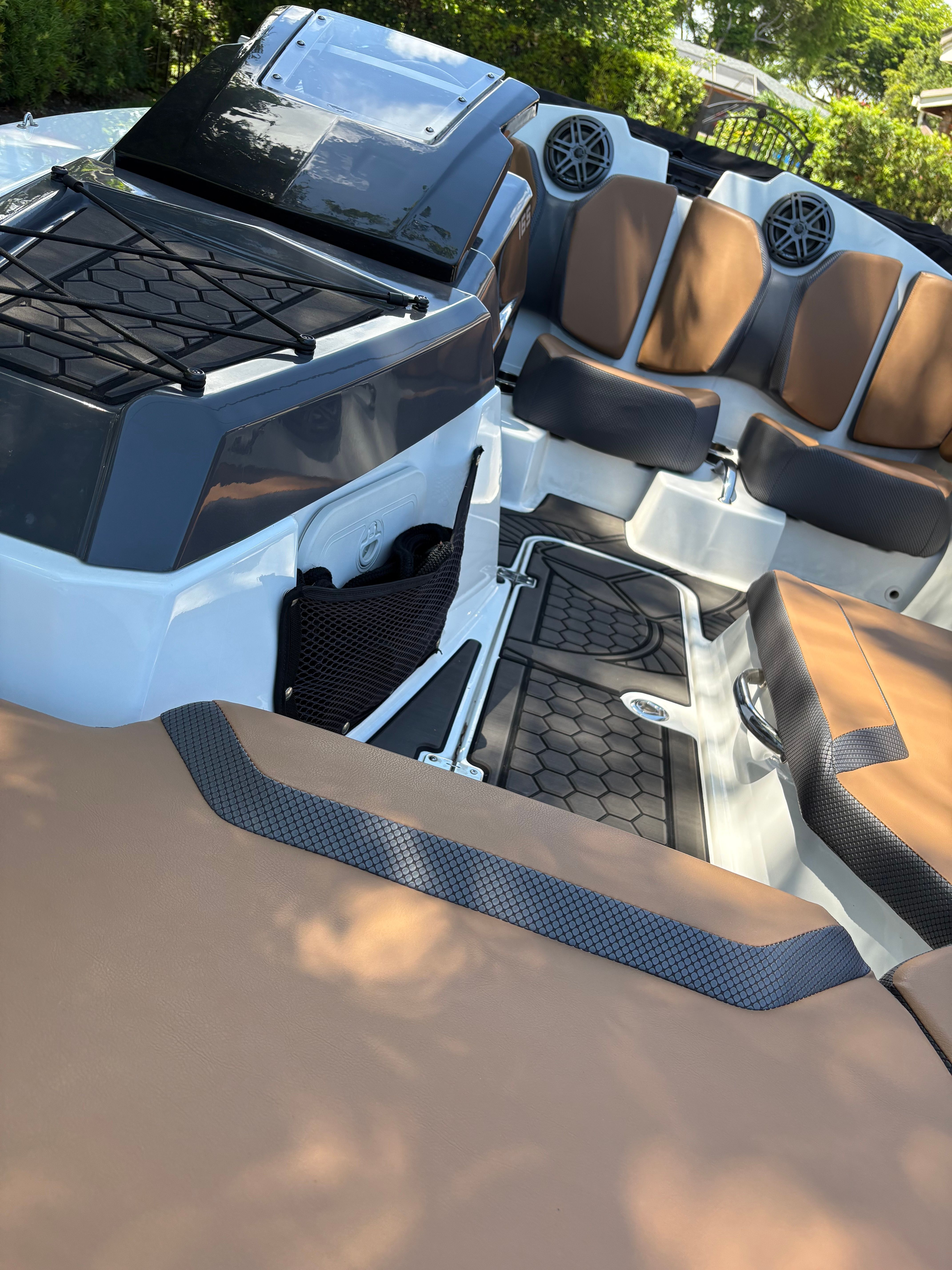 Interior view of a 2022 Scarab 165 ID boat with brown seats and speakers.