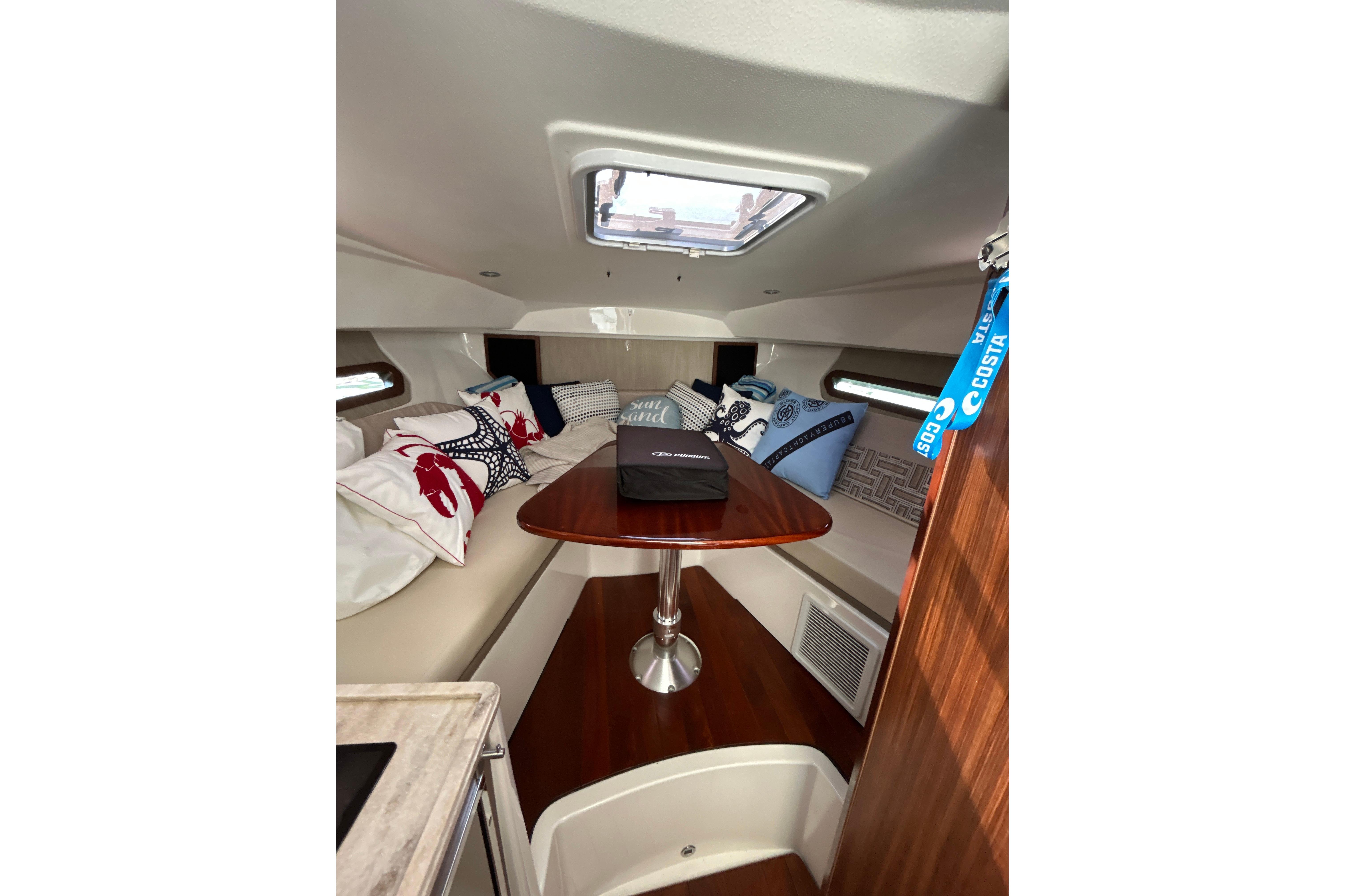 2021 Pursuit OS 325 Offshore cabin interior with cozy seating and decorative pillows.