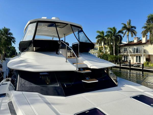 Aquila 44 yacht, 2022 model, docked near waterfront homes with palm trees.
