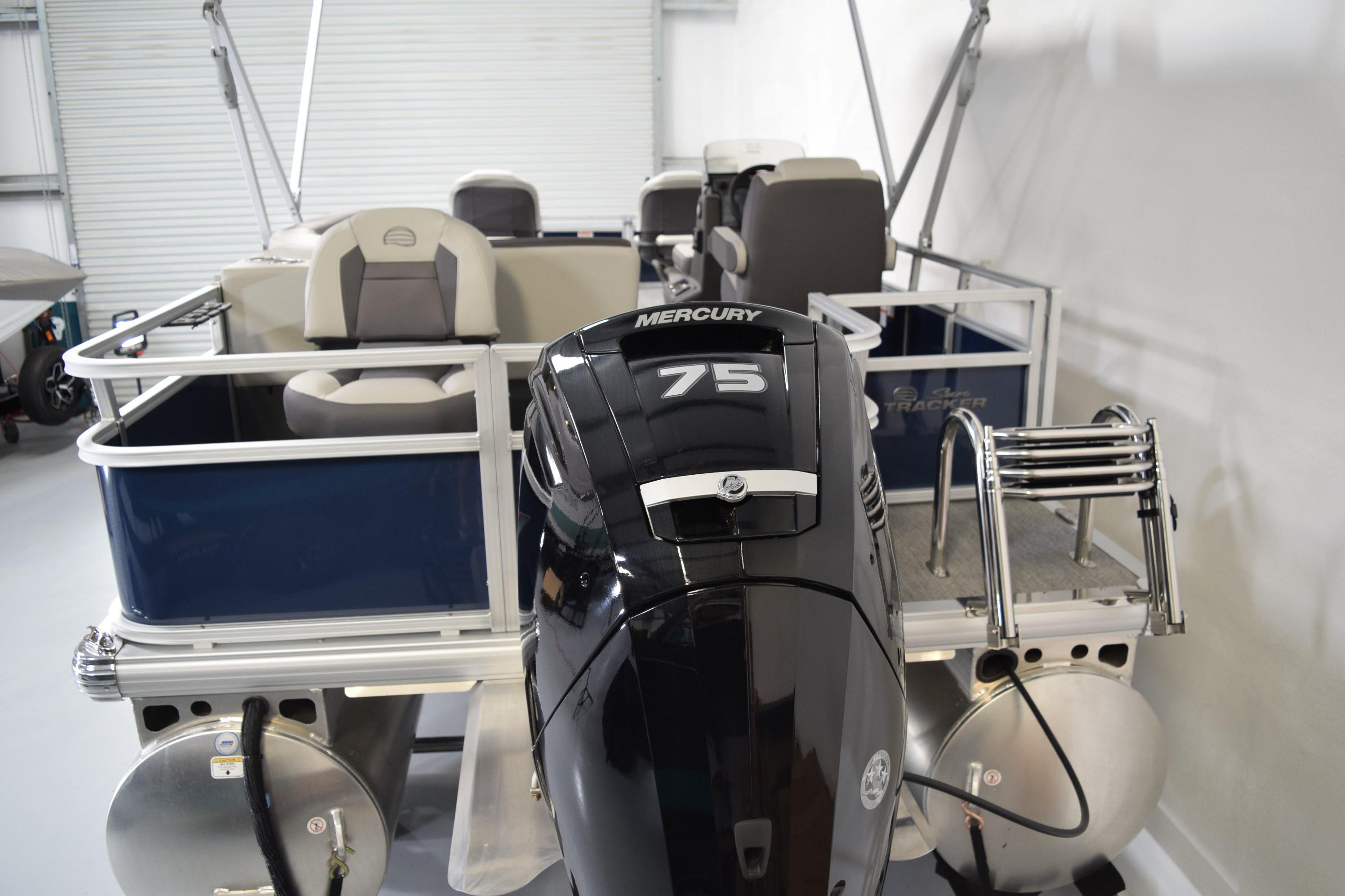 2026 Sun Tracker Bass Buggy 18 DLX pontoon boat with Mercury 75 engine in a showroom.