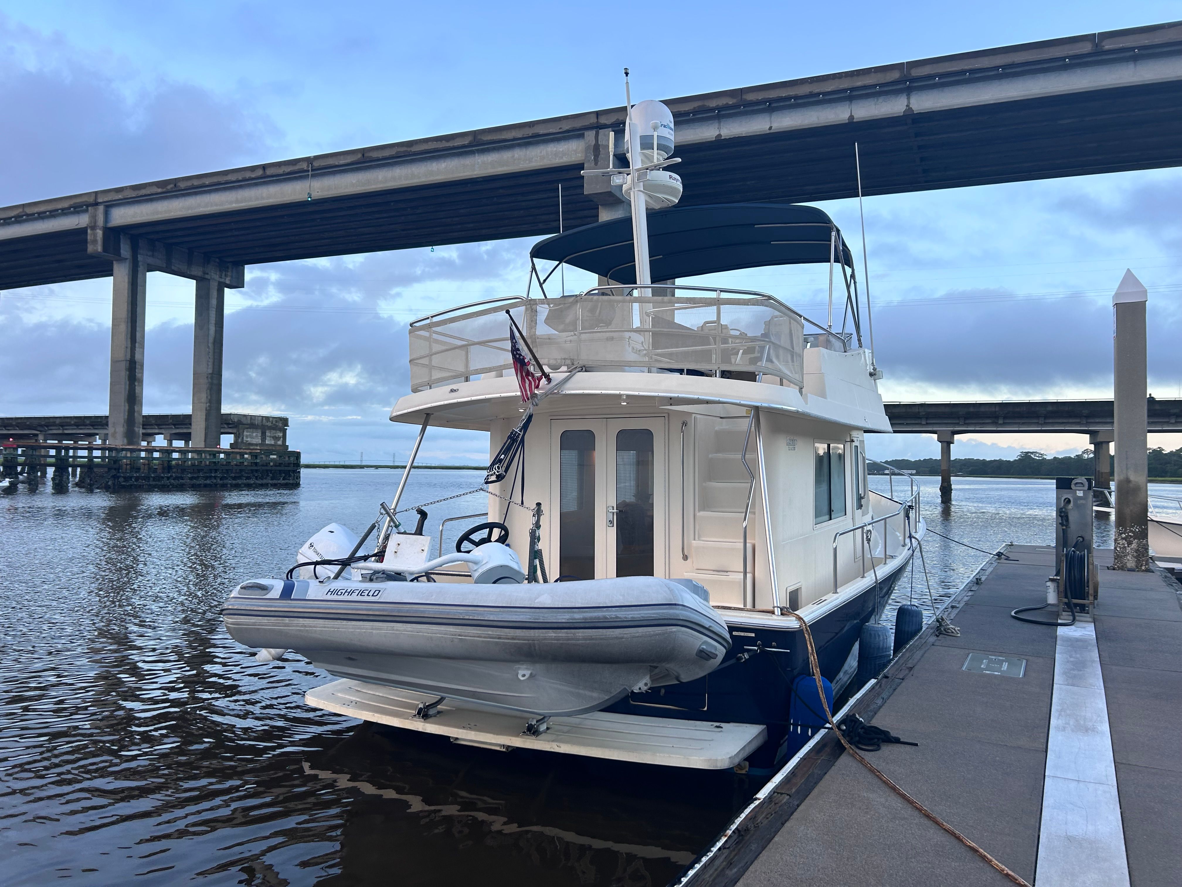 A 2005 Mainship 34 Trawler docked under a bridge.