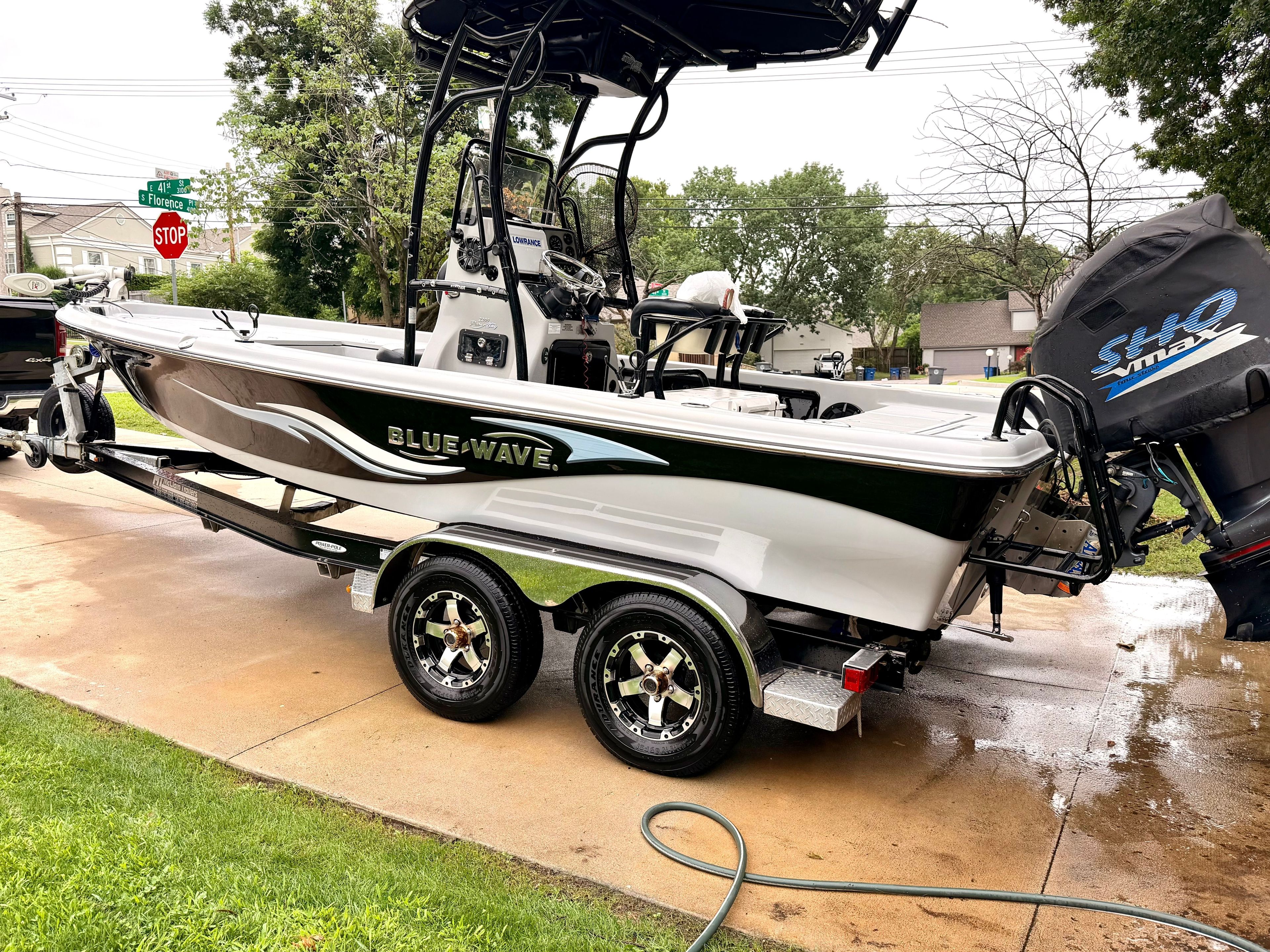 A 2013 Blue Wave Pure Bay 2200 boat on a trailer in a driveway.