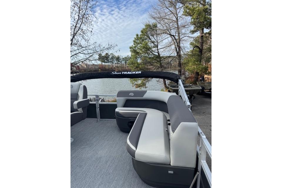 2026 Sun Tracker Bass Buggy 16 XL Select pontoon boat with seating, near a scenic lake.