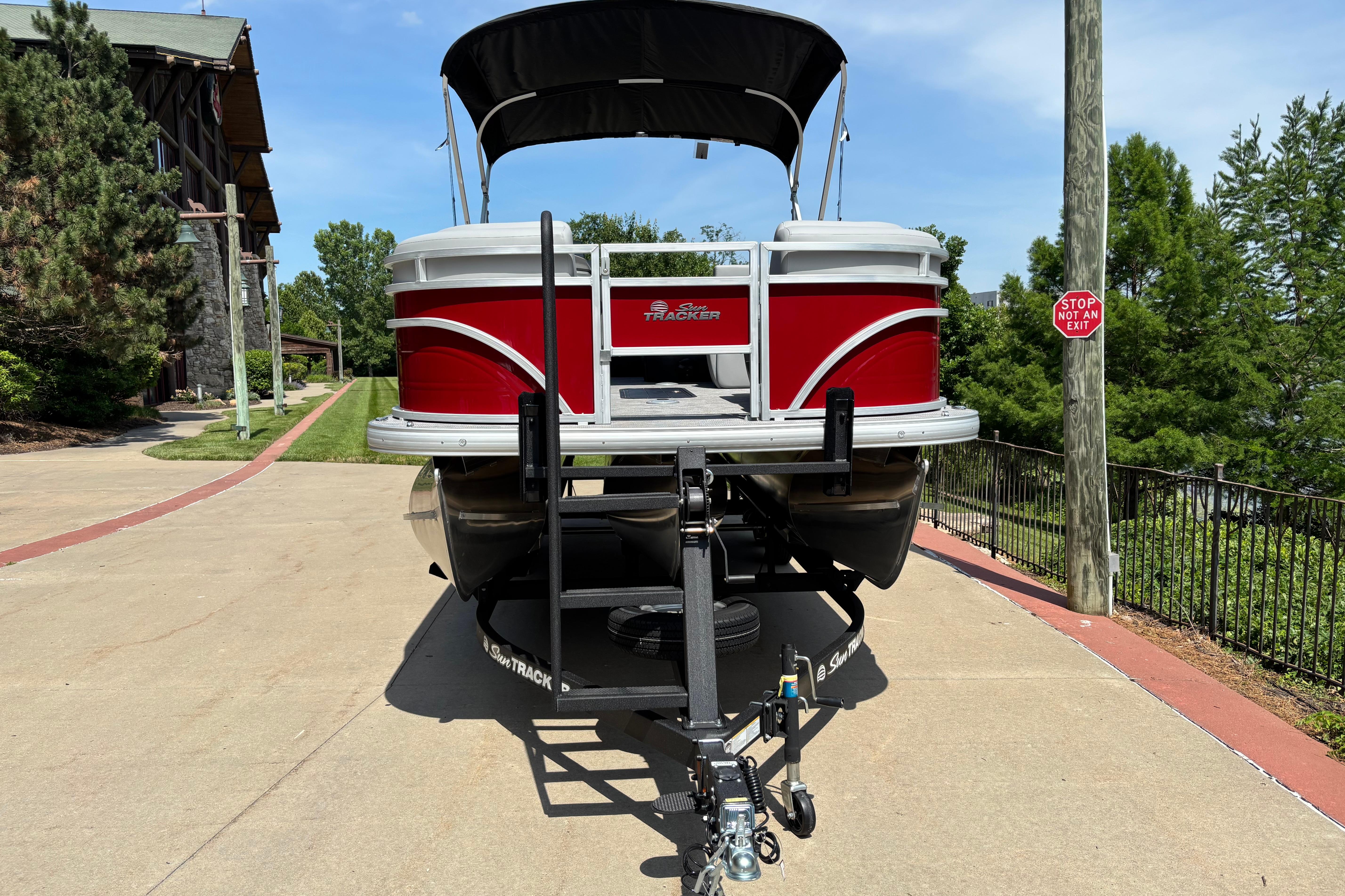 2026 Sun Tracker SportFish 22 XP3 pontoon boat on trailer, parked outdoors.