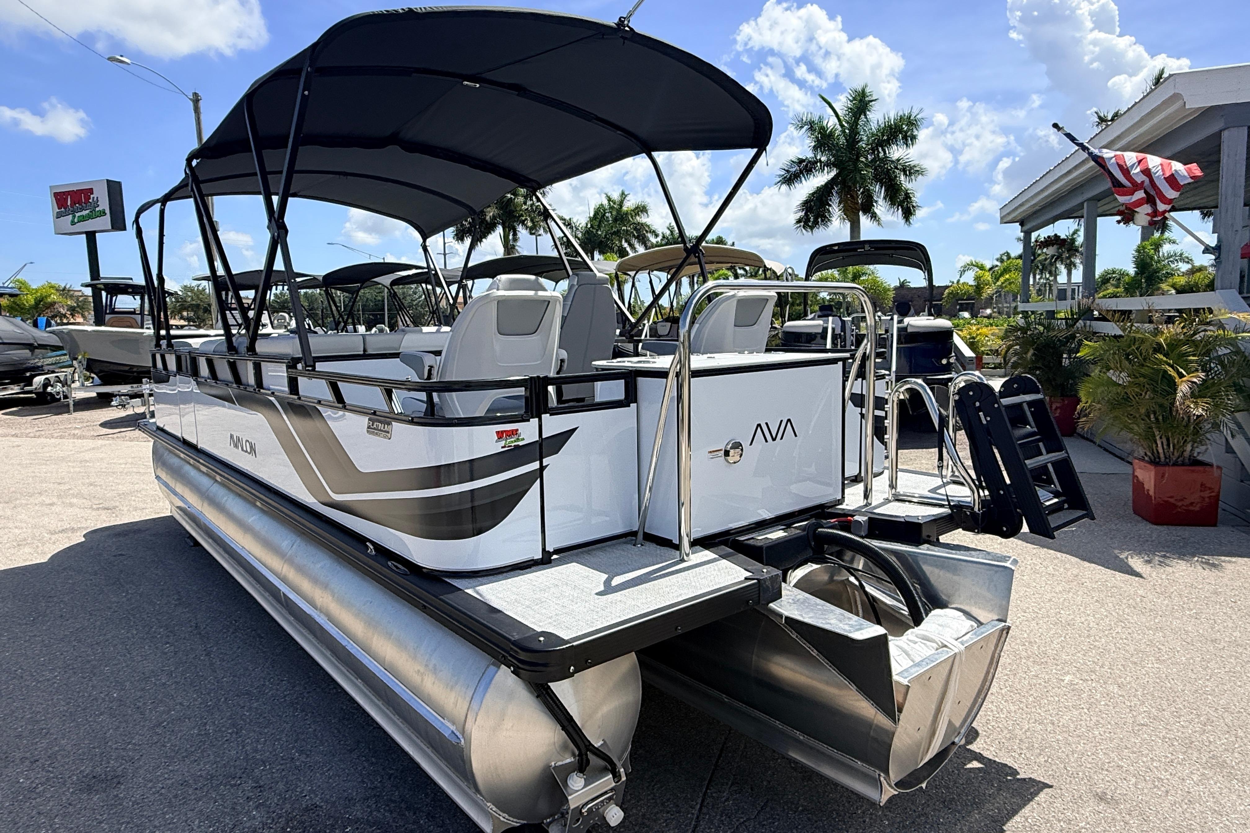 2026 Avalon 2385 Venture 85 Tri Toon boat with canopy, parked outdoors under a sunny sky.