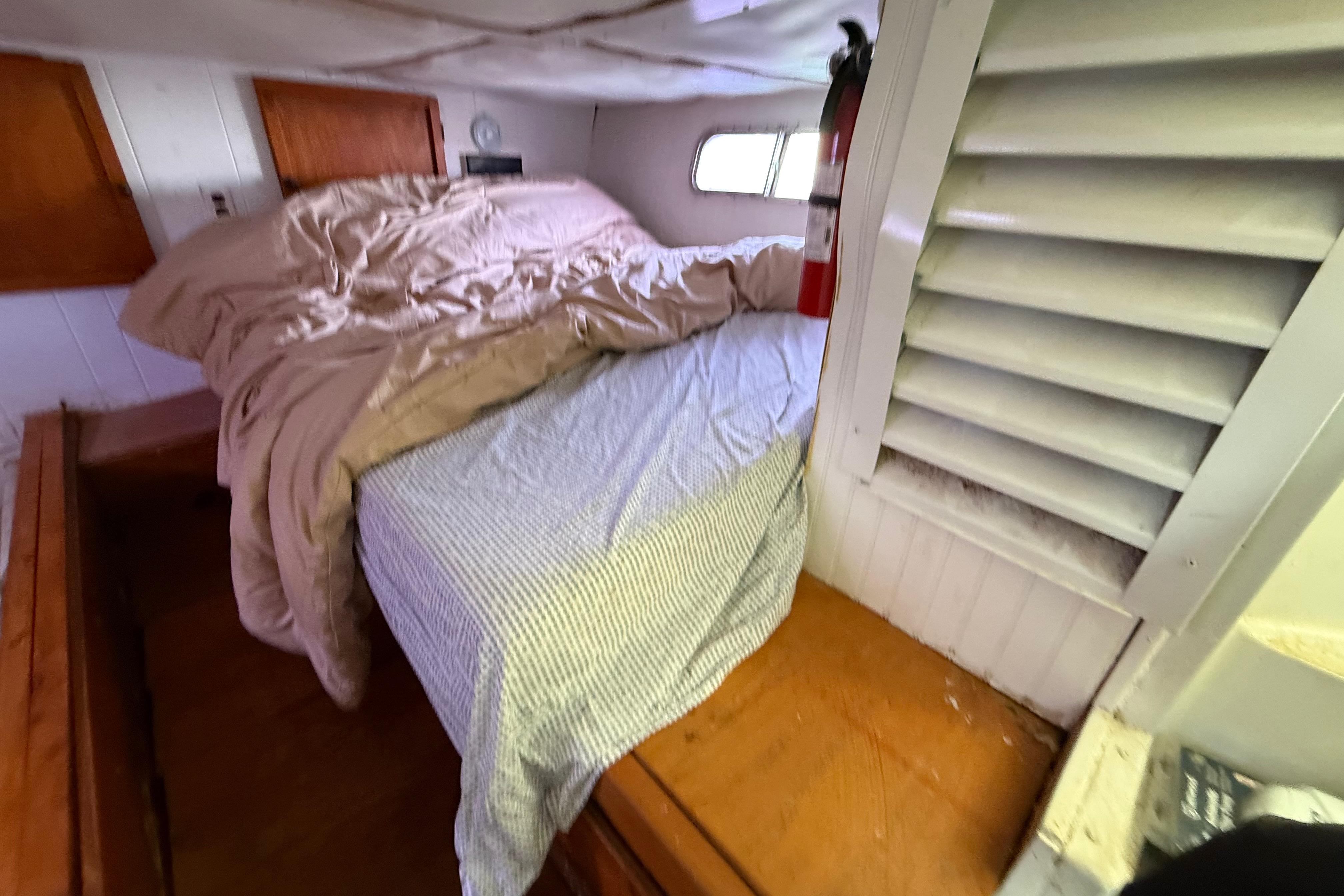 Cozy bedroom interior of 1983 Holiday Mansion 37 Barracuda boat with bed and fire extinguisher.