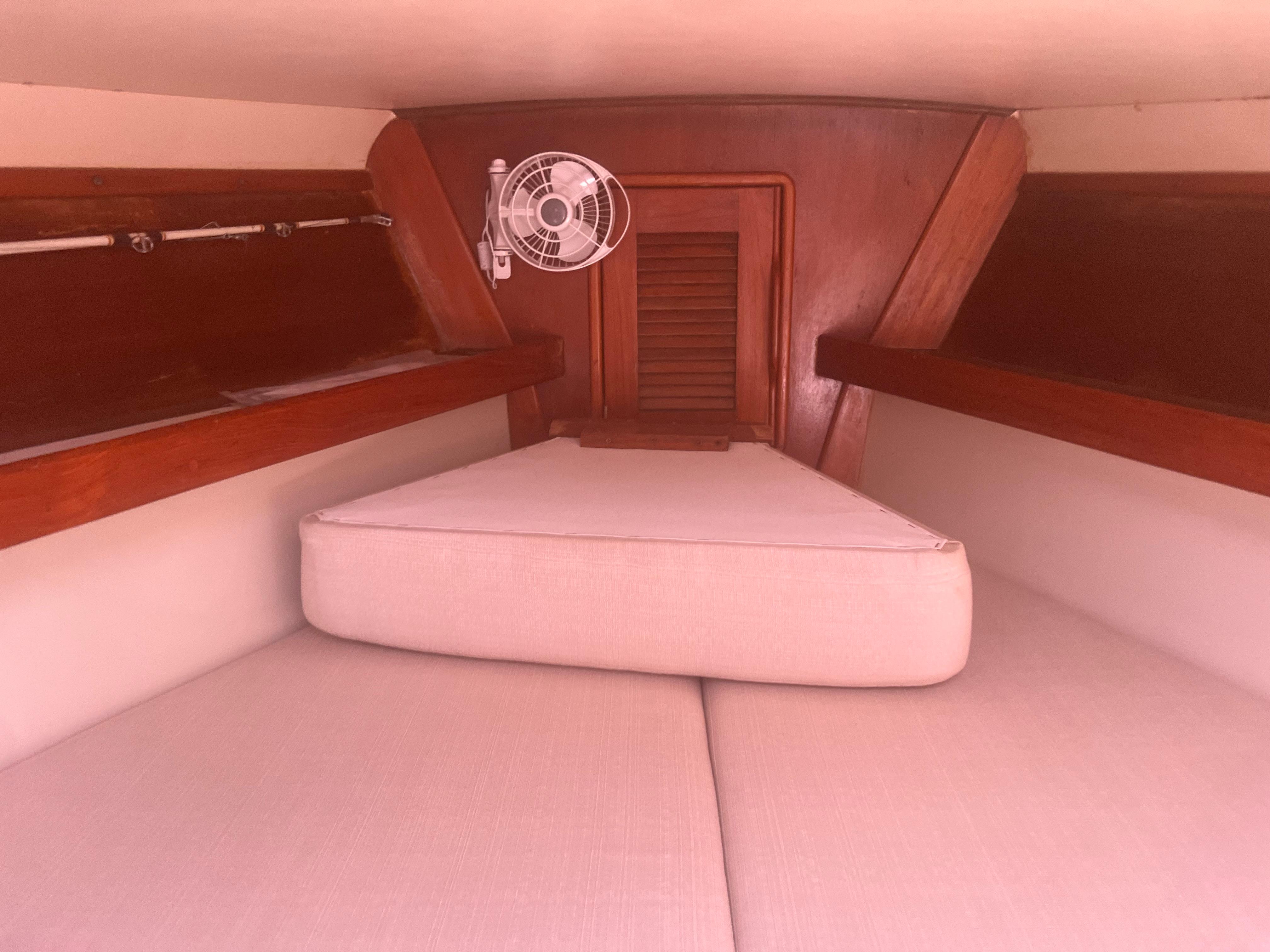 Cozy cabin interior of 1990 Irwin 38 sailboat with wooden accents and fan.