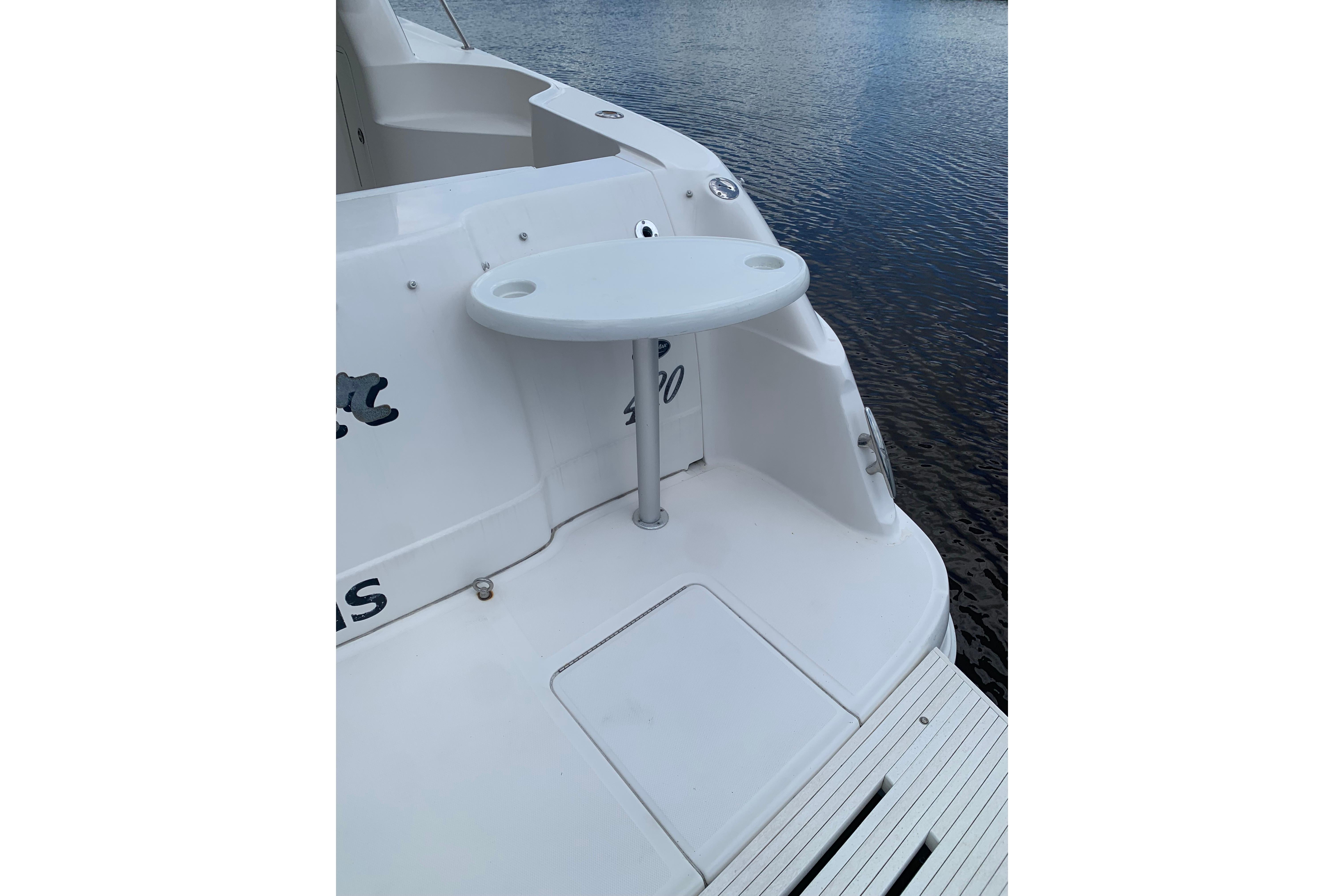 2004 Sea Ray 420 Sedan Bridge boat stern with small table, docked on calm water.