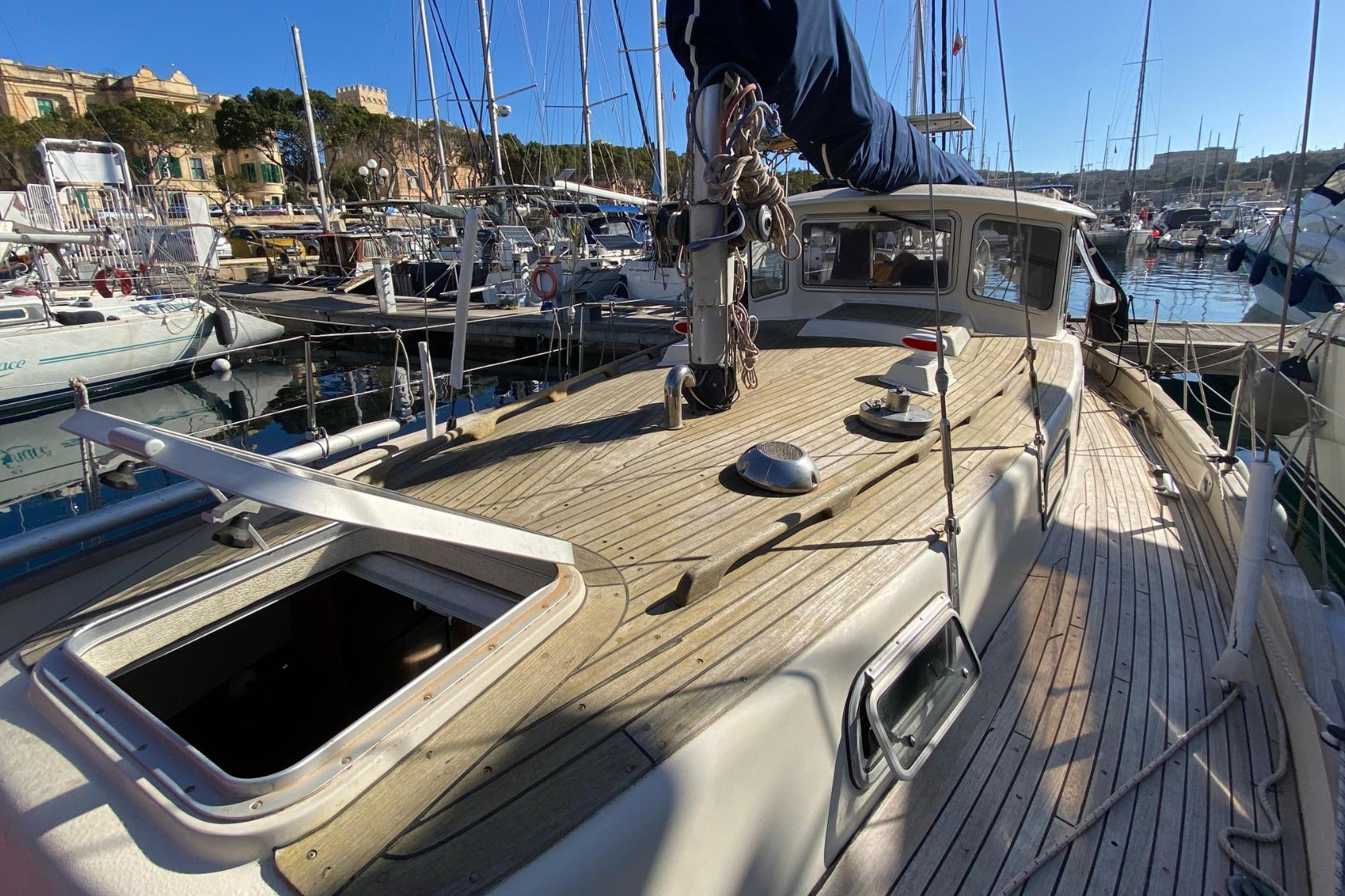1983 Hallberg-Rassy 94 Kutter sailboat docked in a sunny marina.