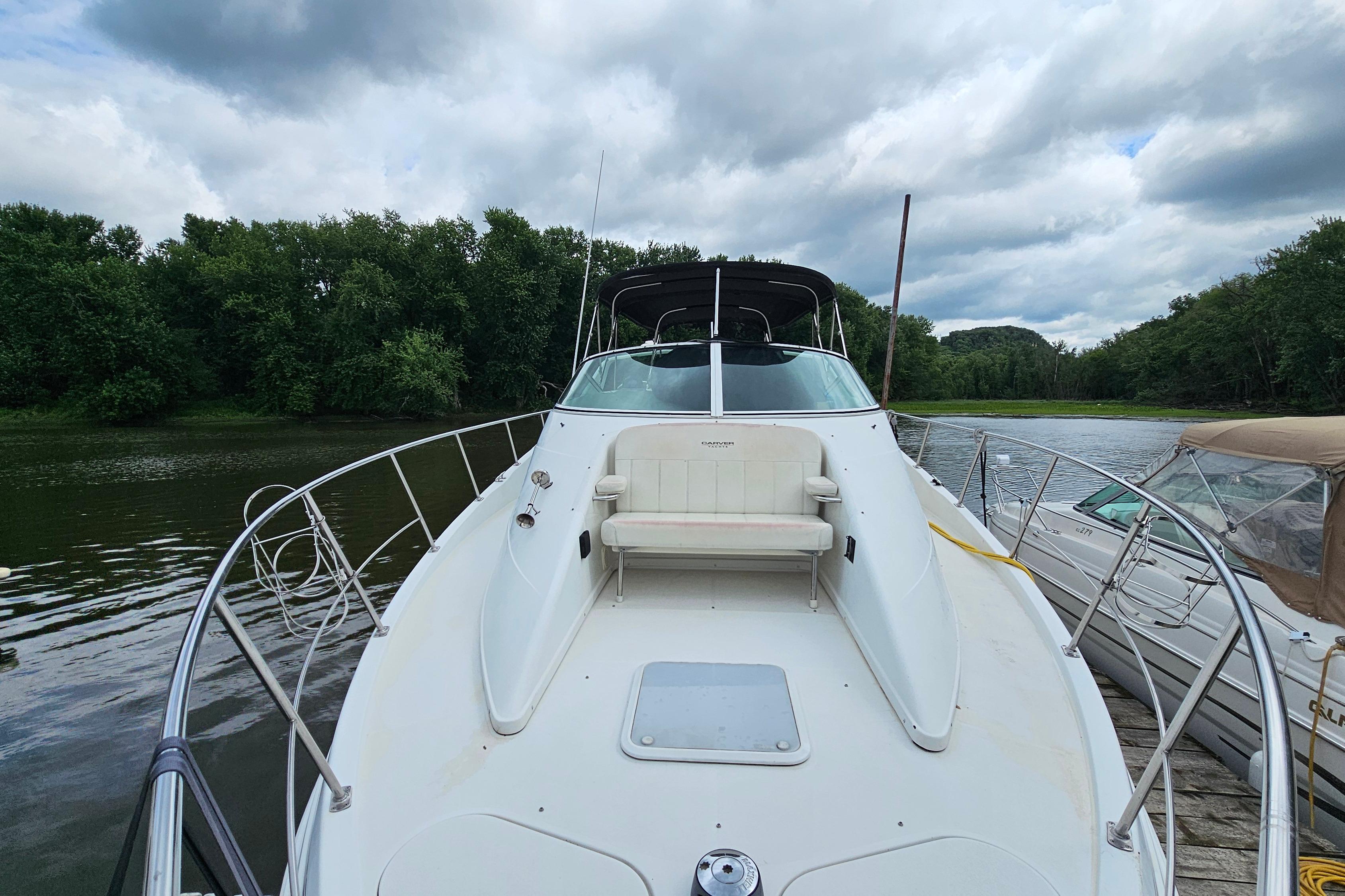 1999 Carver 350 Mariner yacht docked on a serene river with lush greenery.
