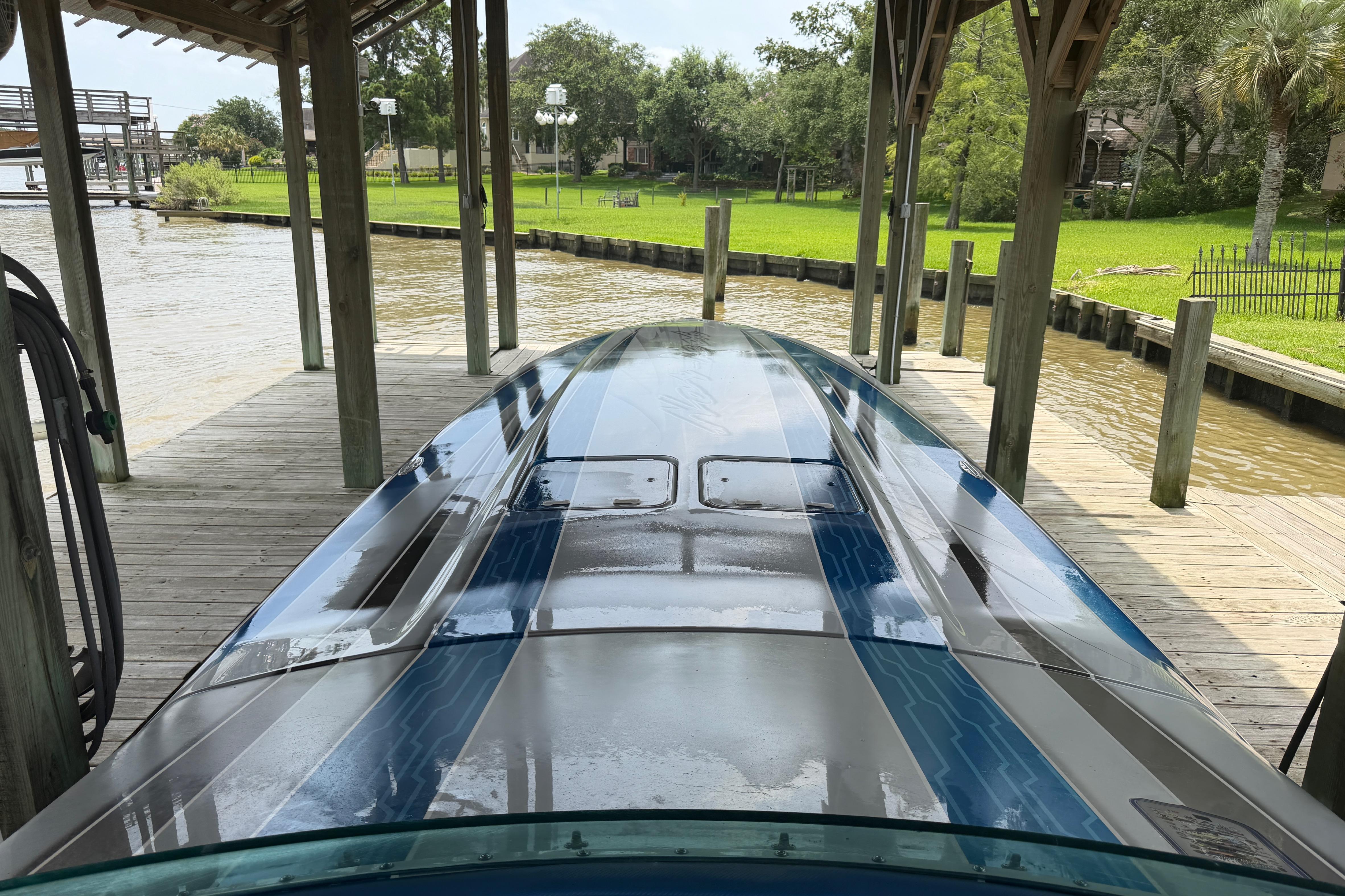 2013 Nor-Tech 477 SPX Vee Bottom boat docked under a wooden shelter.