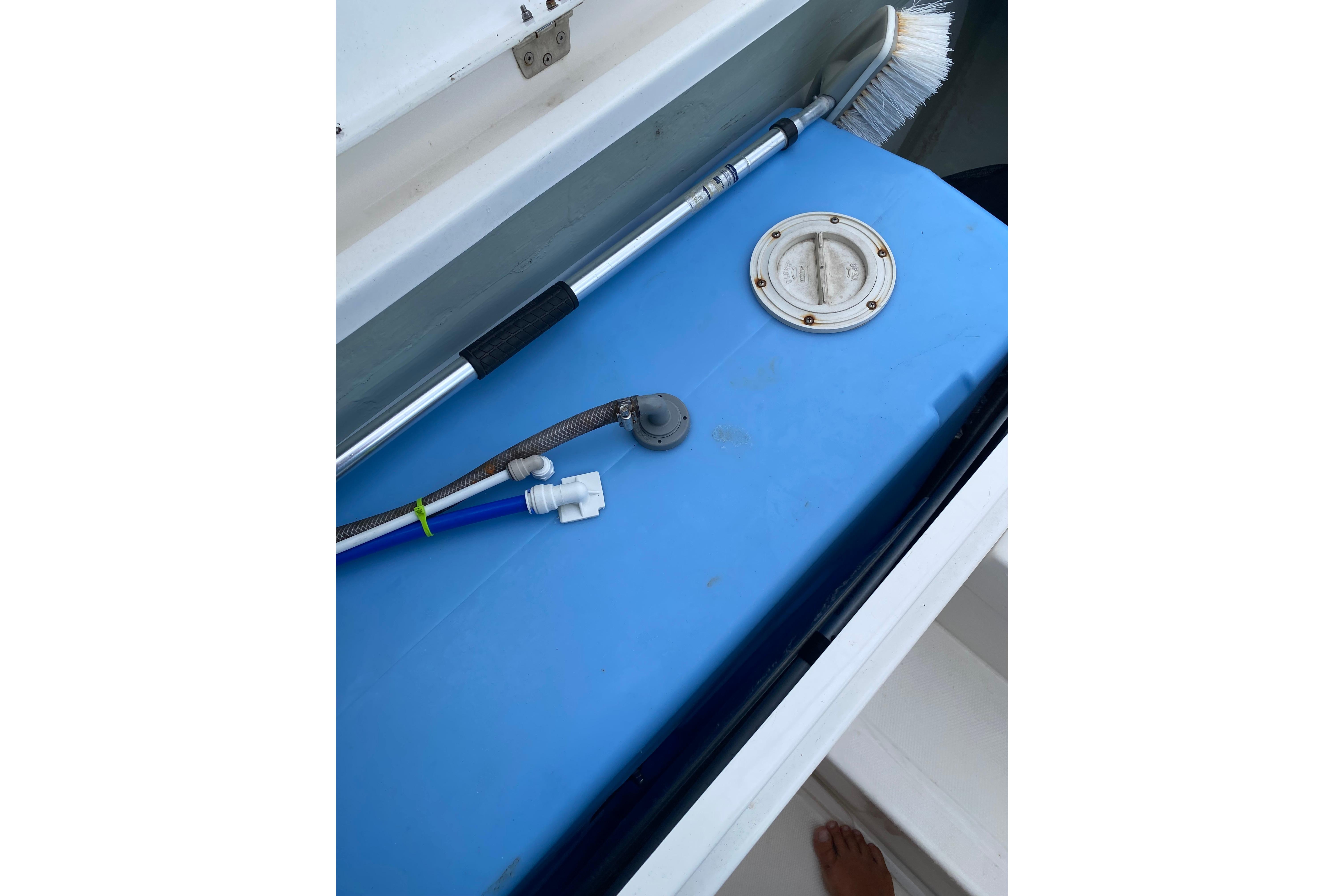Blue storage compartment on 2017 Leopard 40 boat with cleaning brush and hoses.