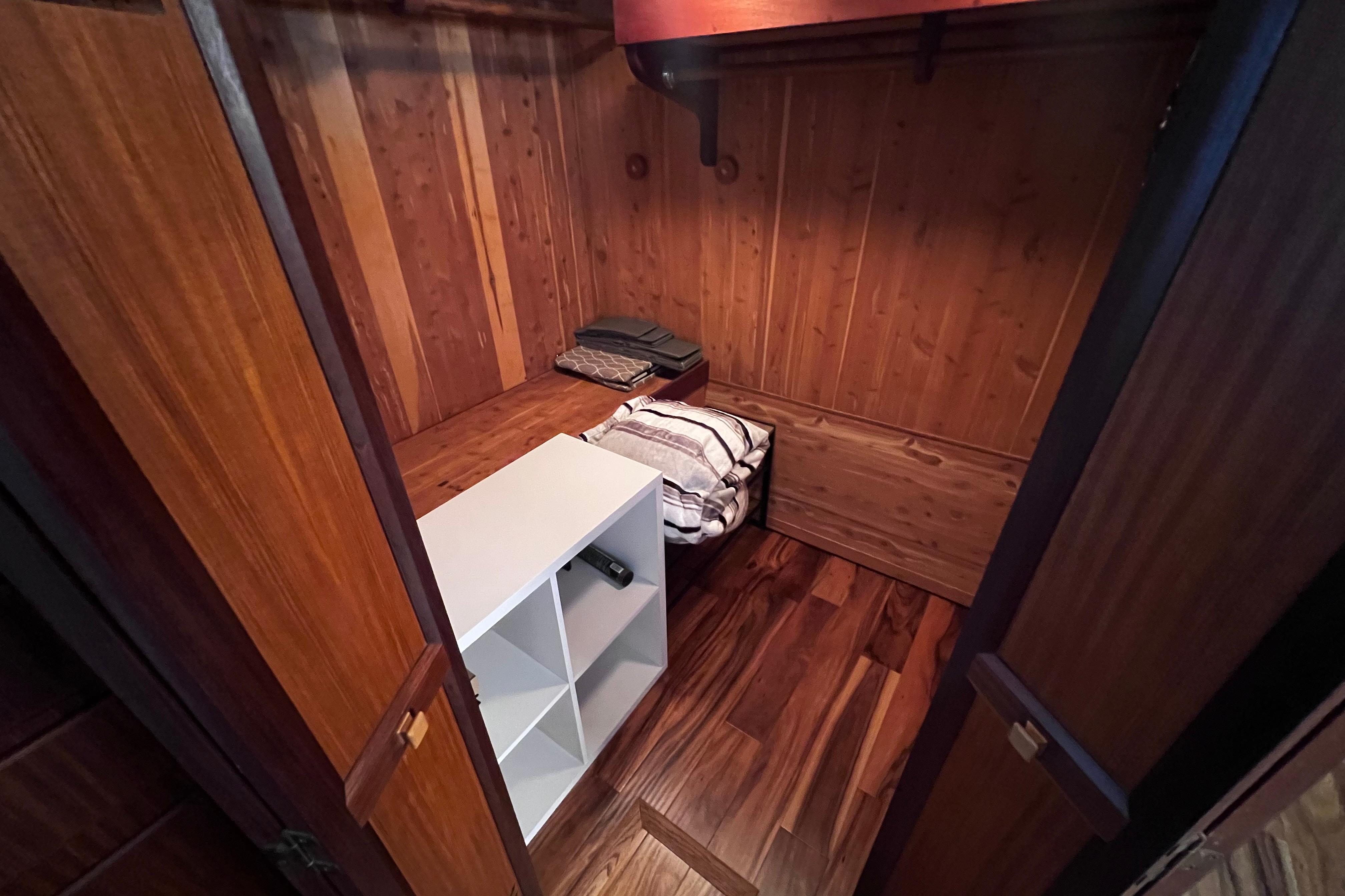 Wood-paneled closet interior on 1987 Hatteras 70 Cockpit Motor Yacht, featuring shelving and folded linens.