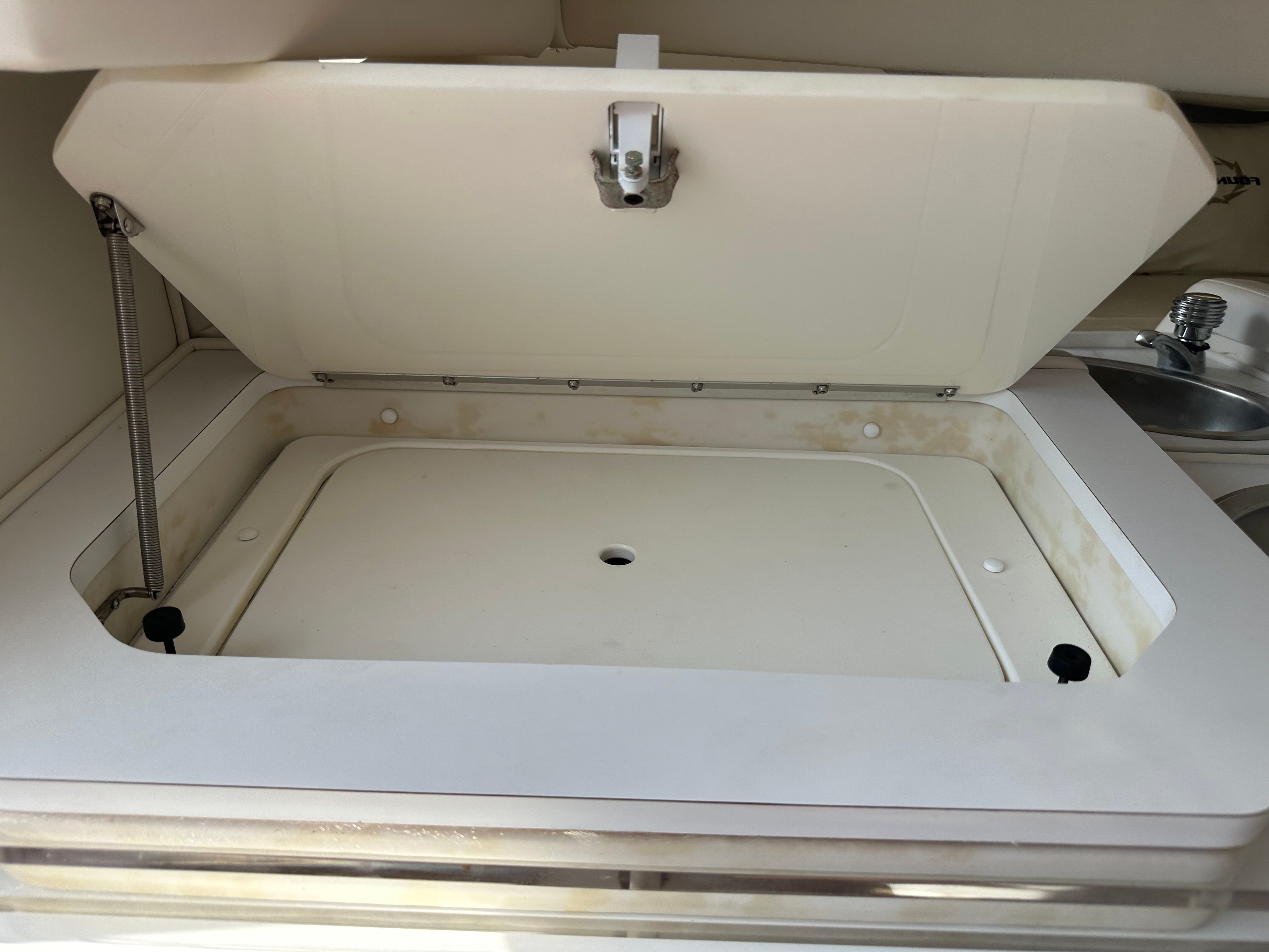 An open storage compartment on a boat with a lift mechanism.