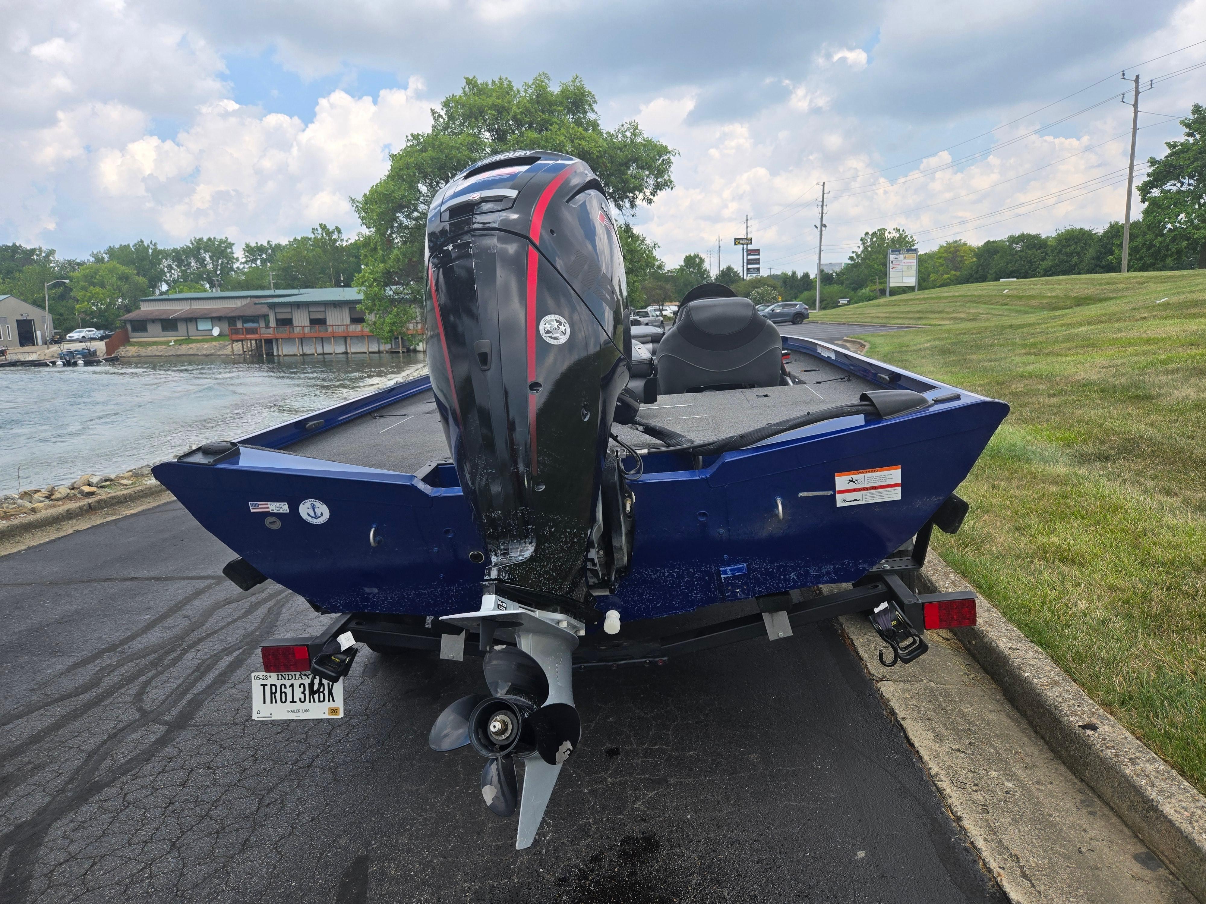 2021 Lowe Stinger 188 boat with outboard motor on a trailer, parked near a lake.