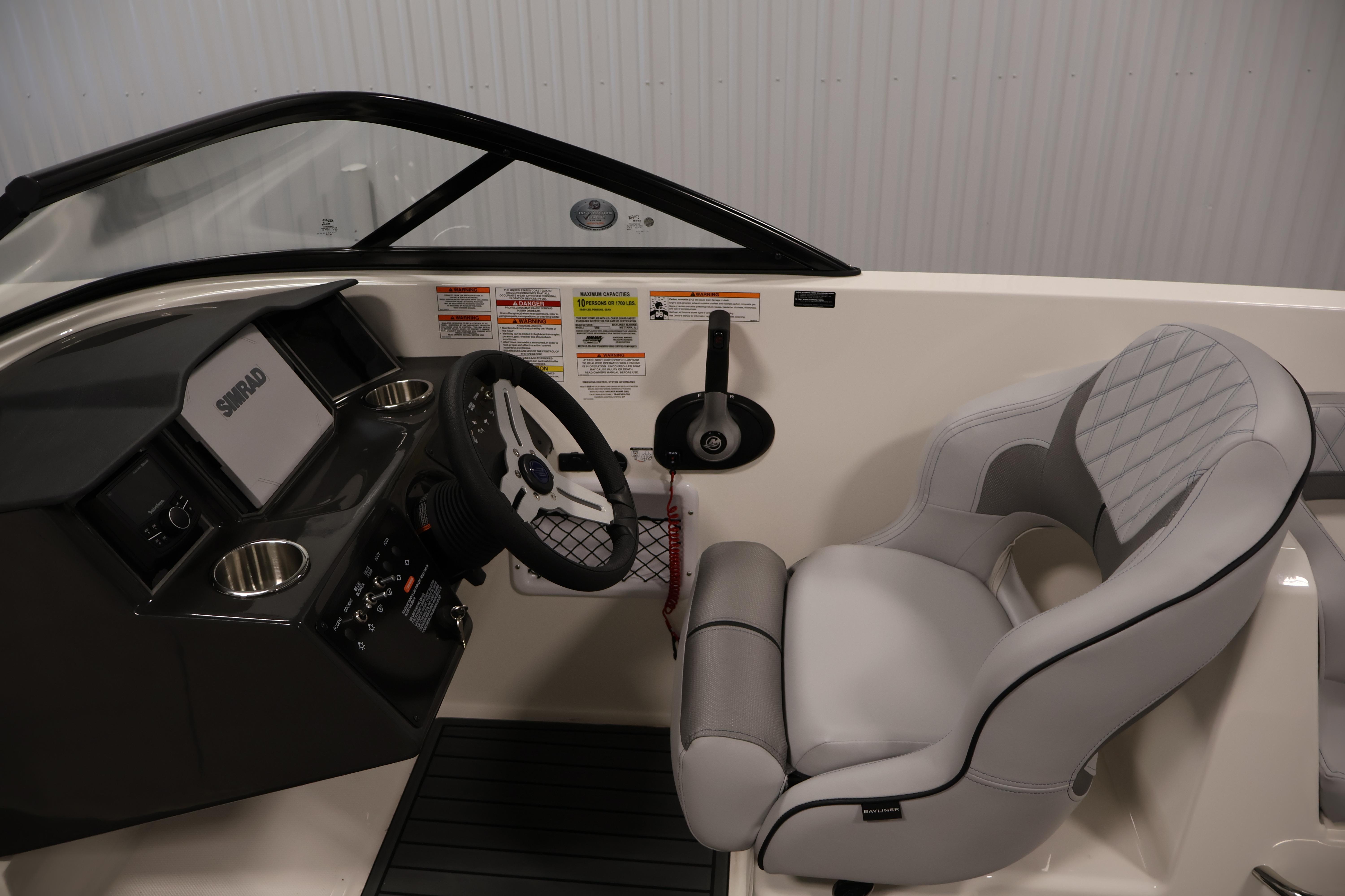 2026 Bayliner VR6 Bowrider I/O cockpit with steering wheel and cushioned seat.