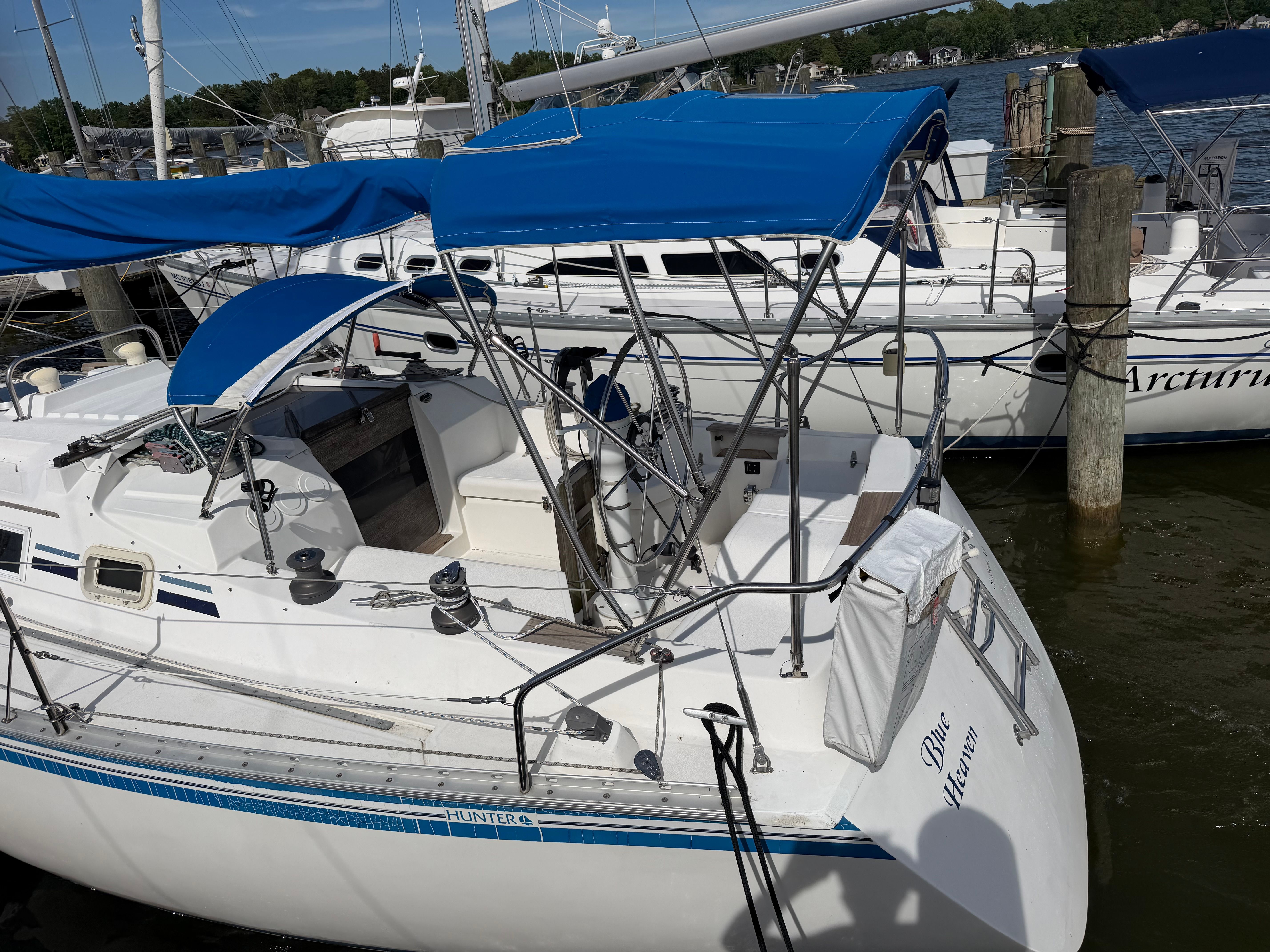 A white sailboat with blue covers docked at the marina.