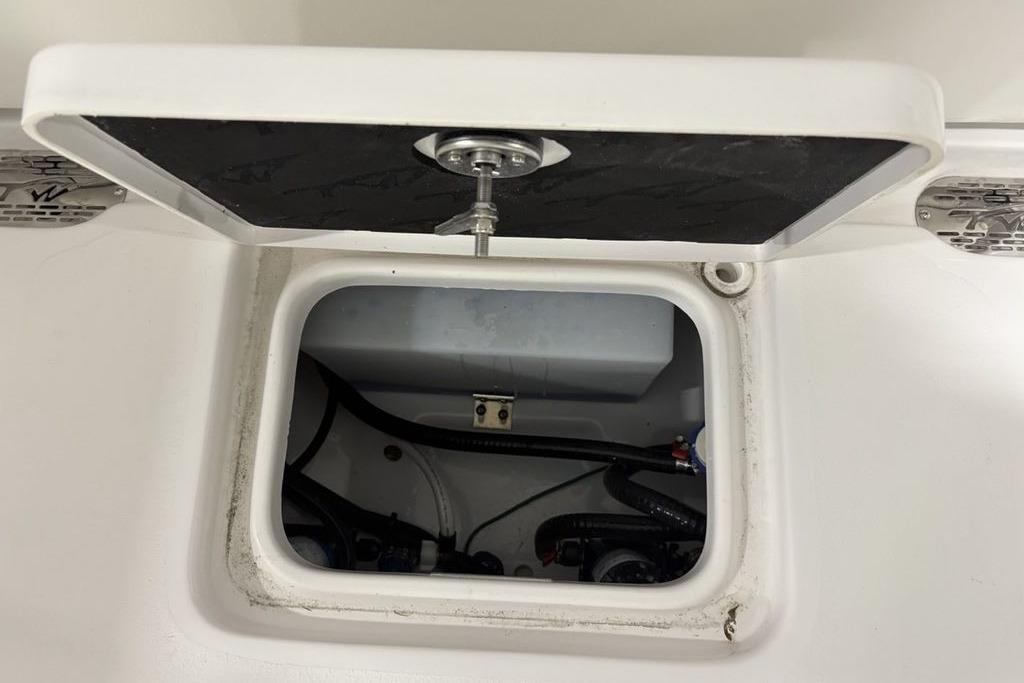 Open hatch on 2026 Tidewater 232 CC Adventure boat, revealing internal wiring and components.