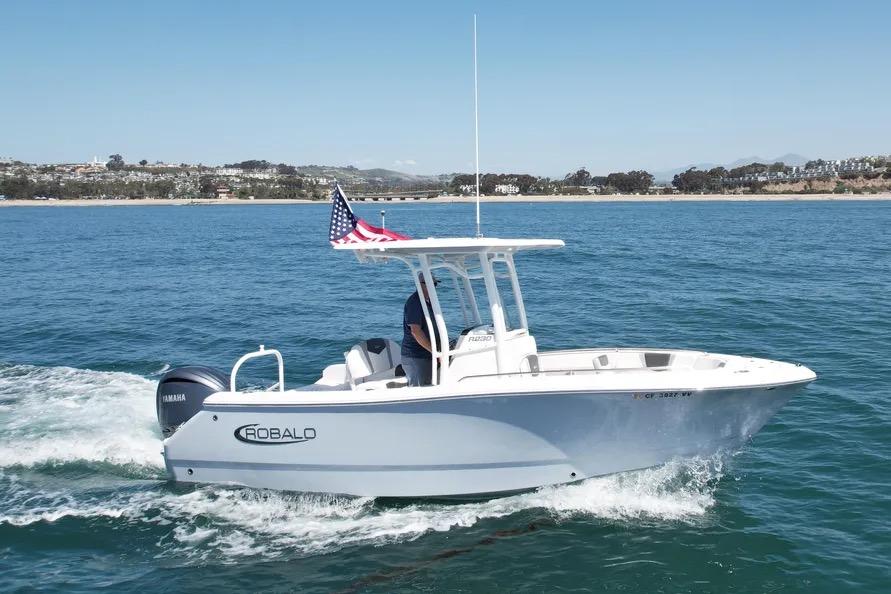 2022 Robalo R230 Center Console boat cruising on open water with American flag.
