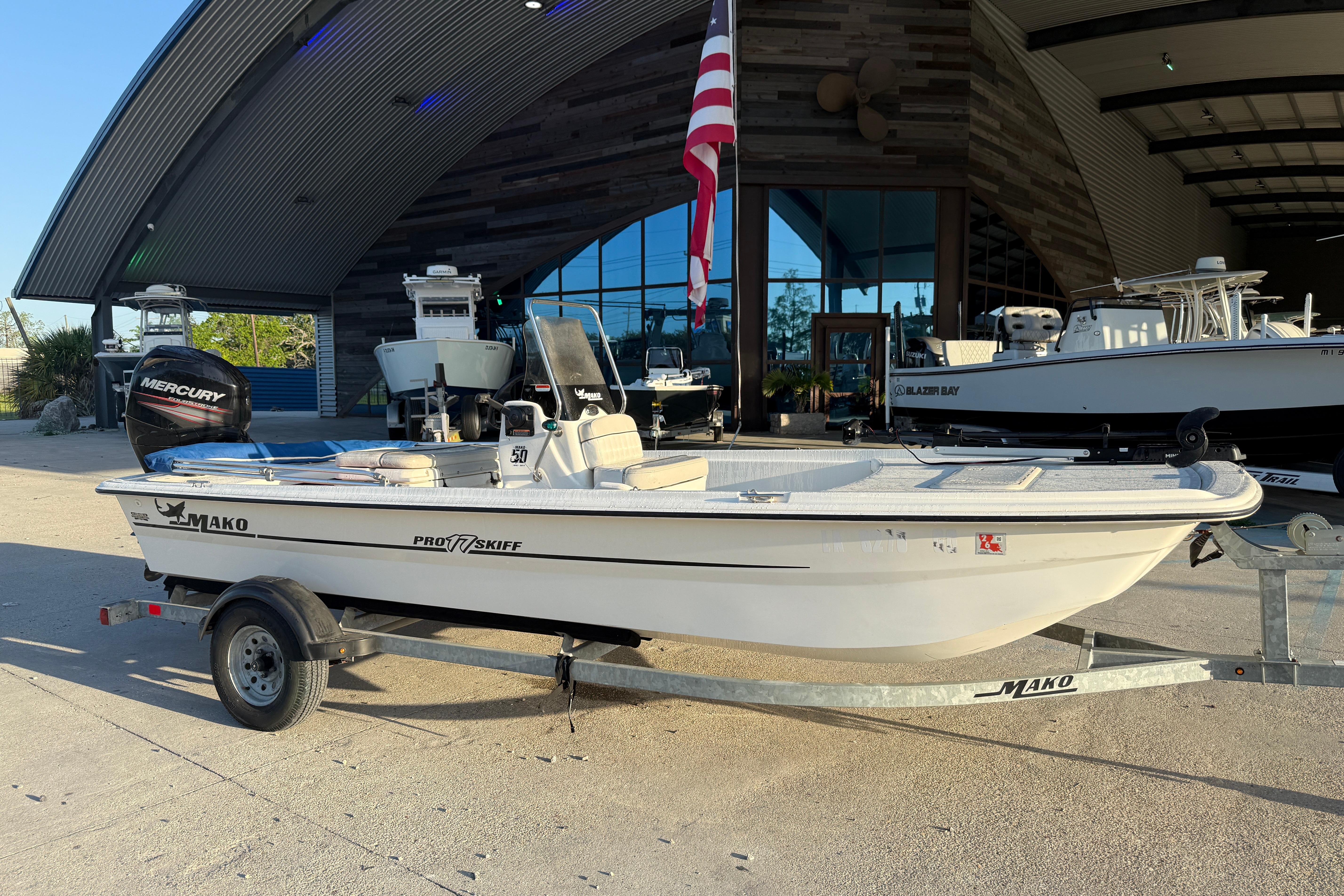2017 Mako Pro Skiff 17 CC boat on trailer outside a modern building.