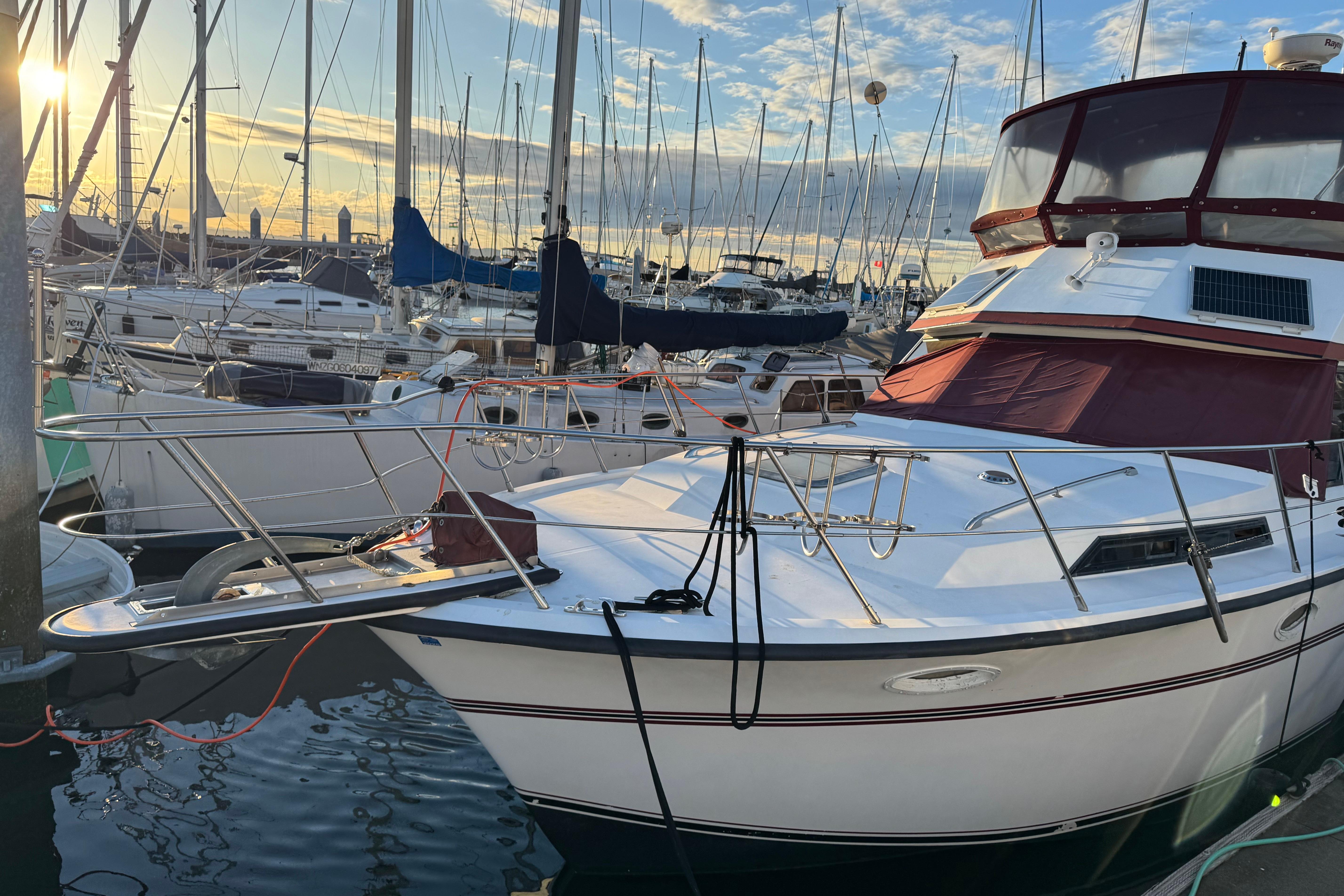 1987 President 37 yacht docked at marina during sunset, surrounded by sailboats.
