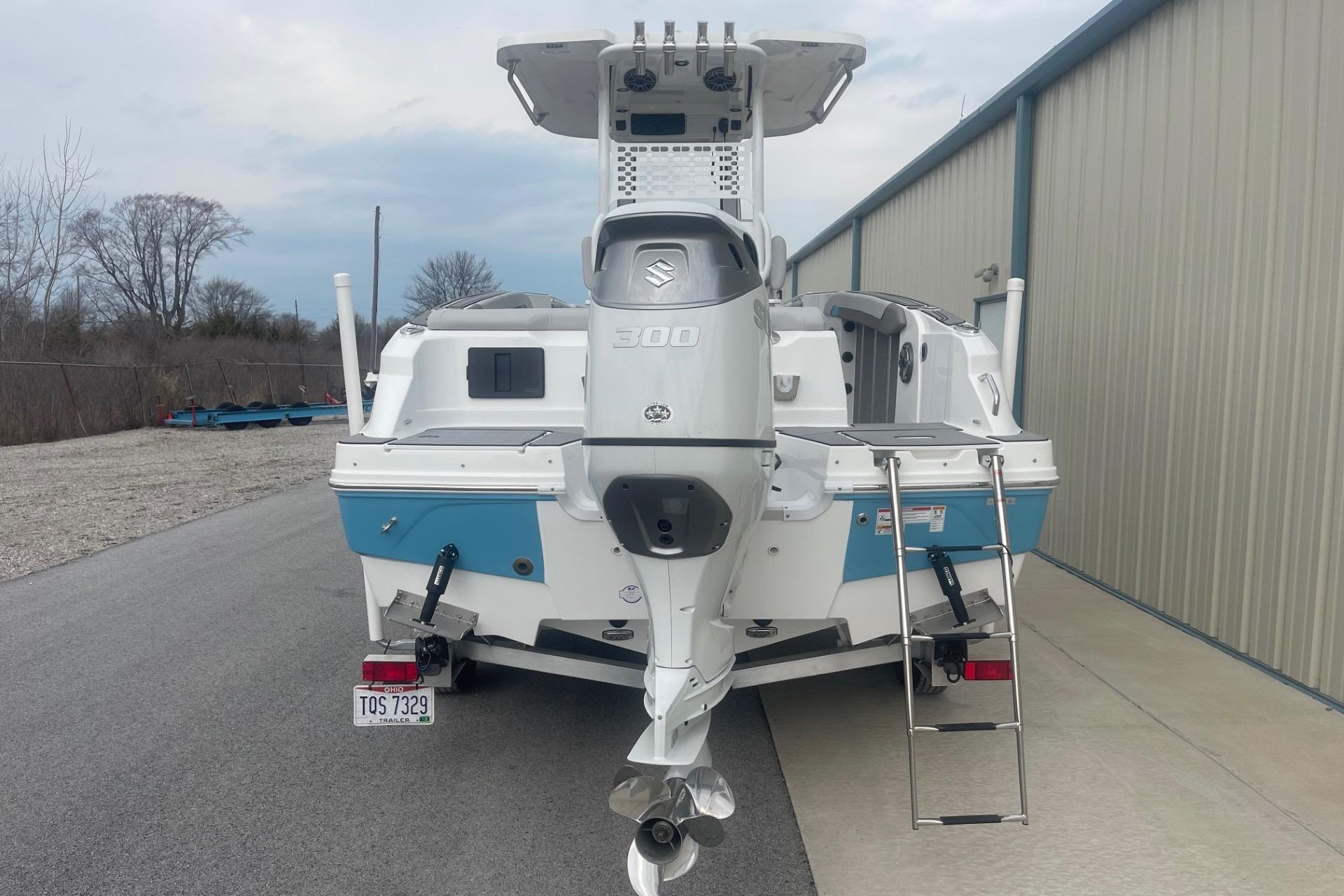2025 Hurricane Center Console 24 OB boat with Suzuki 300 engine, parked near a building.