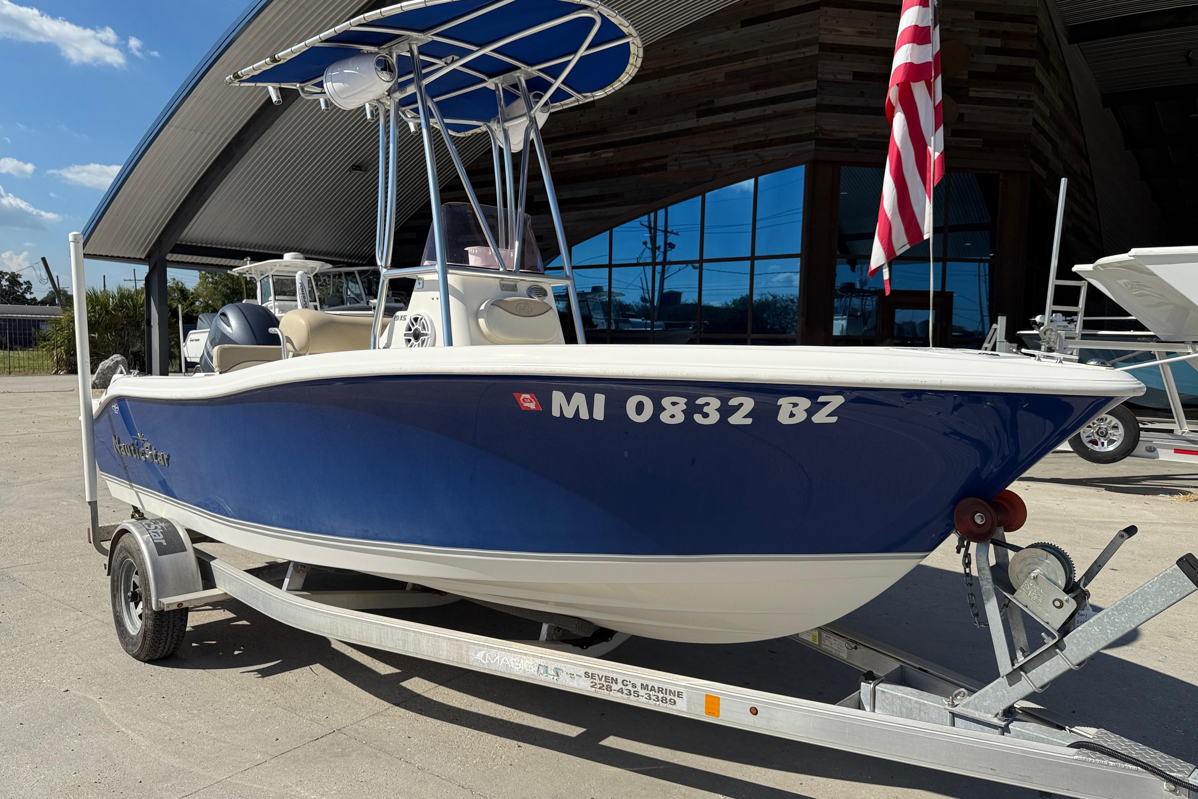 2019 NauticStar 19 XS boat on trailer, blue hull, American flag displayed.