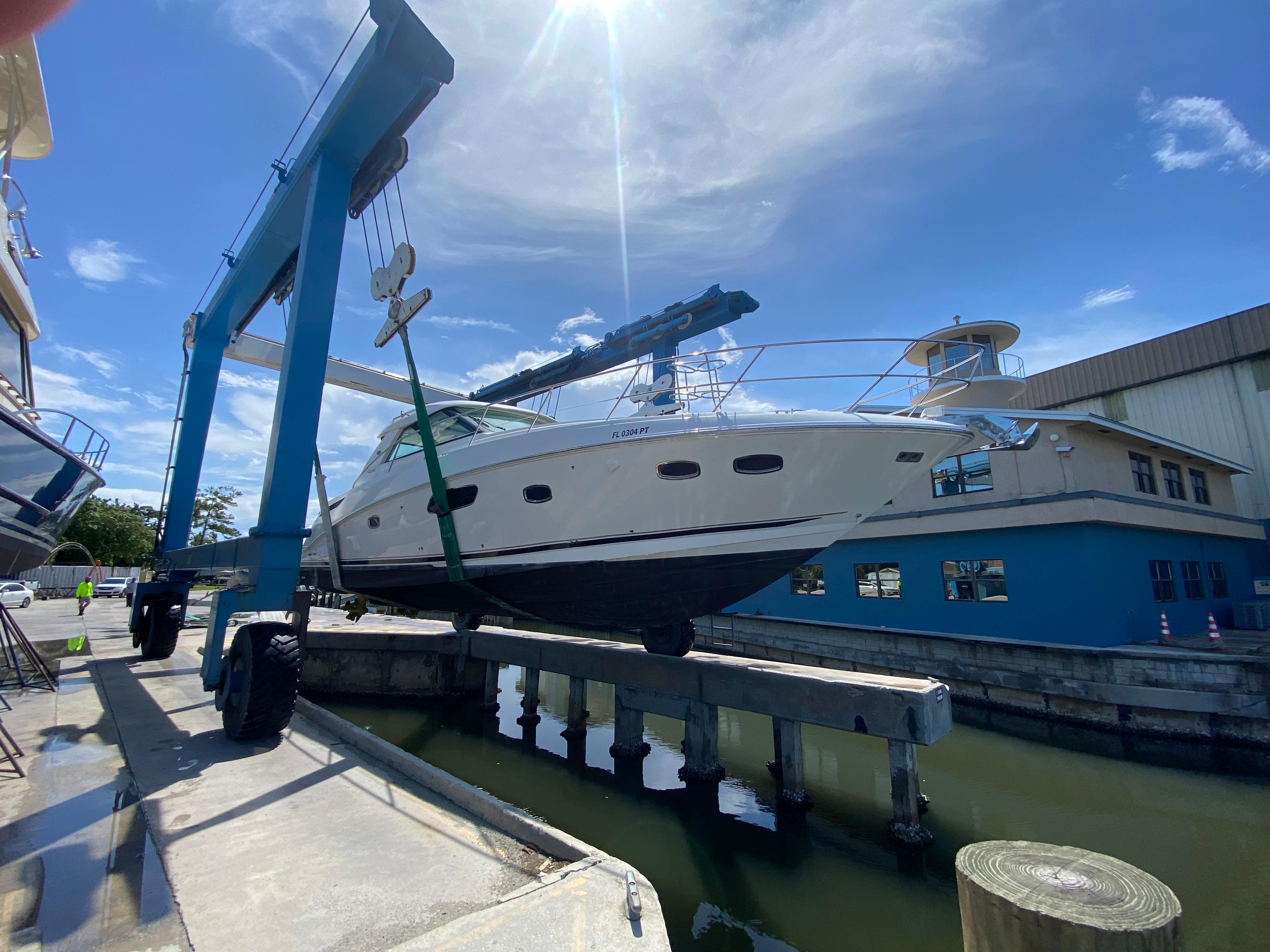 2012 Sea Ray 450 Sundancer yacht lifted by crane at marina.