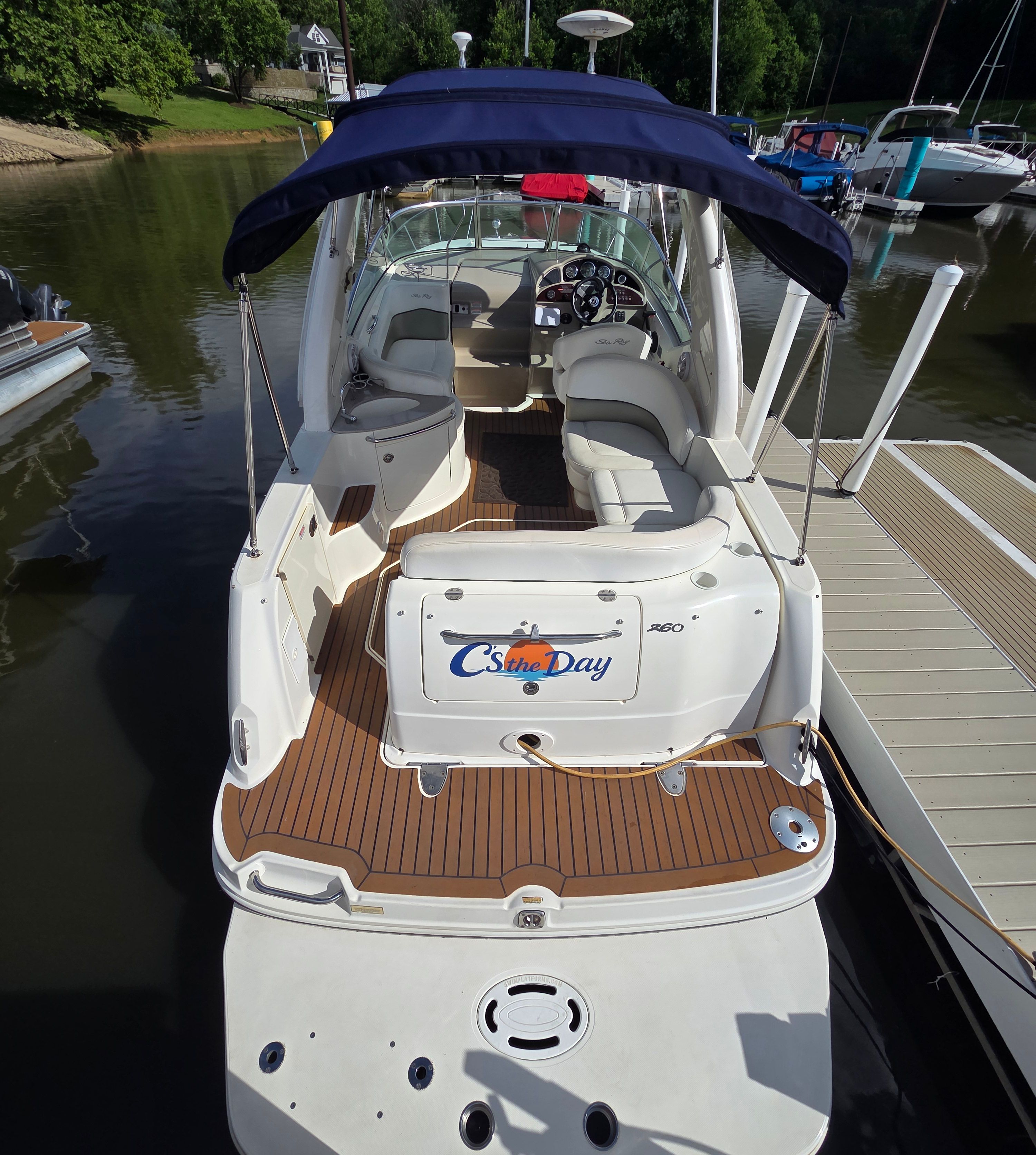 2005 Sea Ray Sundancer 260 at dock with open cockpit and blue canopy.