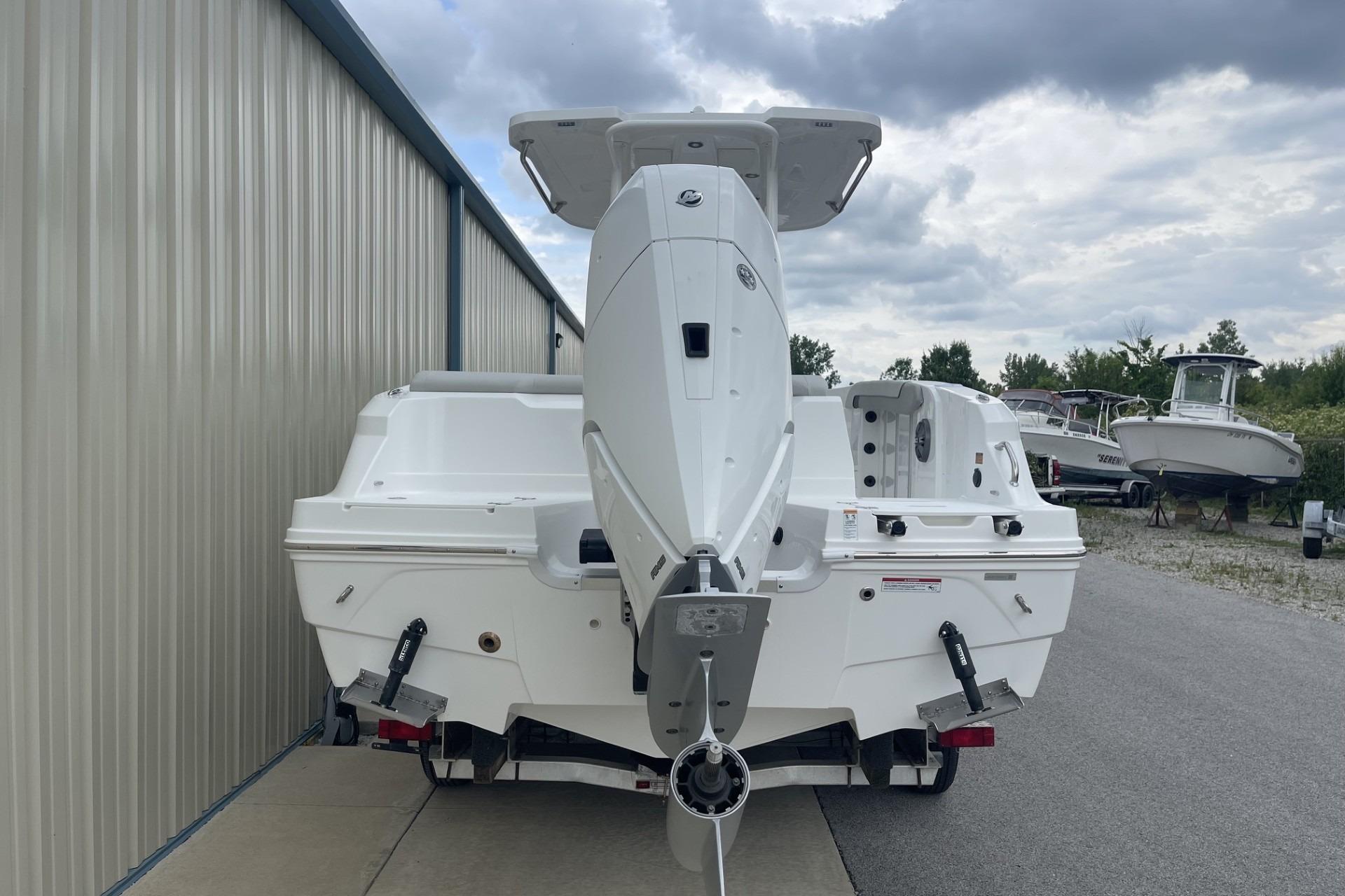 2026 Hurricane Center Console 24 OB boat, rear view, parked near a metal building under cloudy skies.