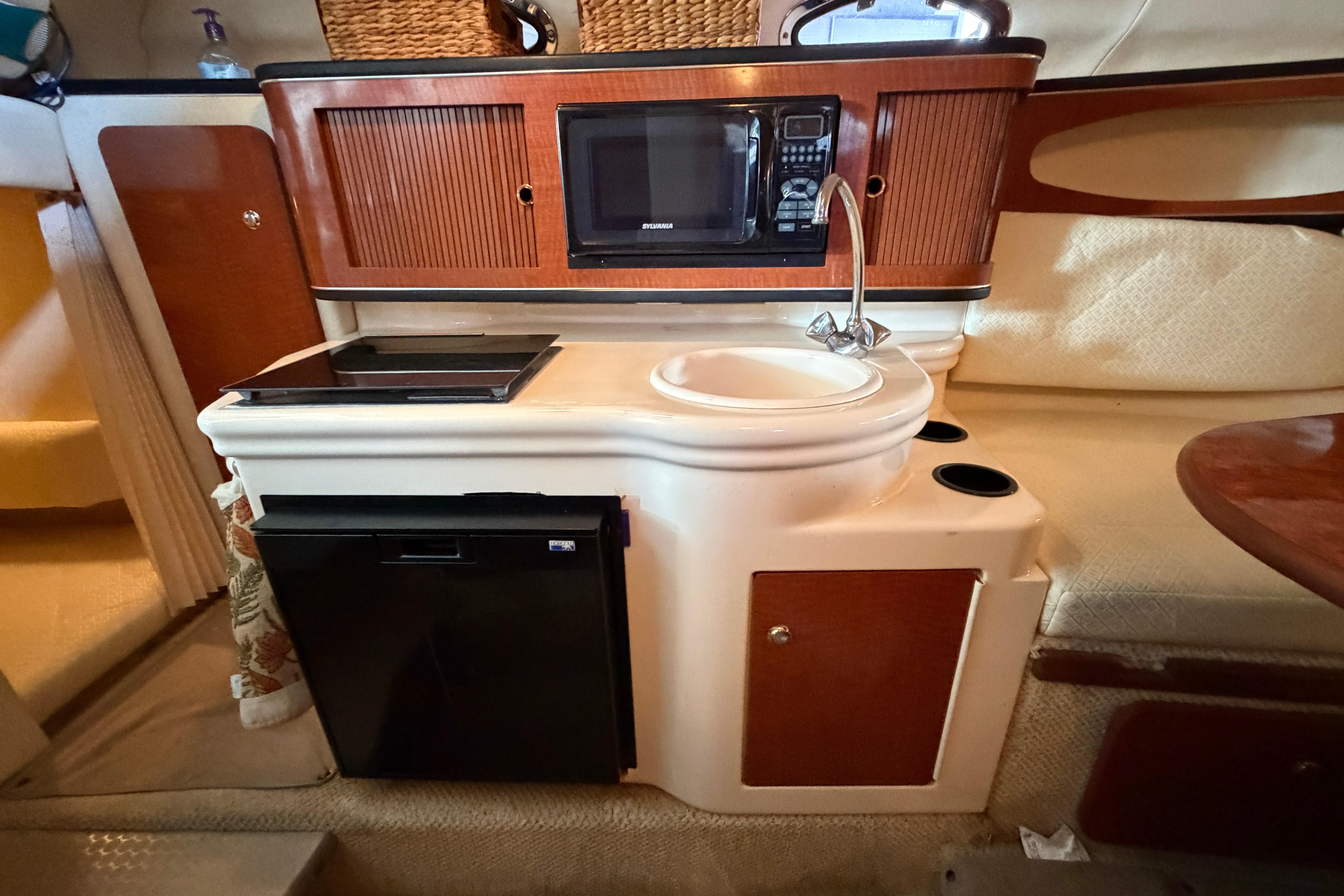 2004 Sea Ray Sundancer 260 interior with kitchenette, microwave, sink, and mini fridge.