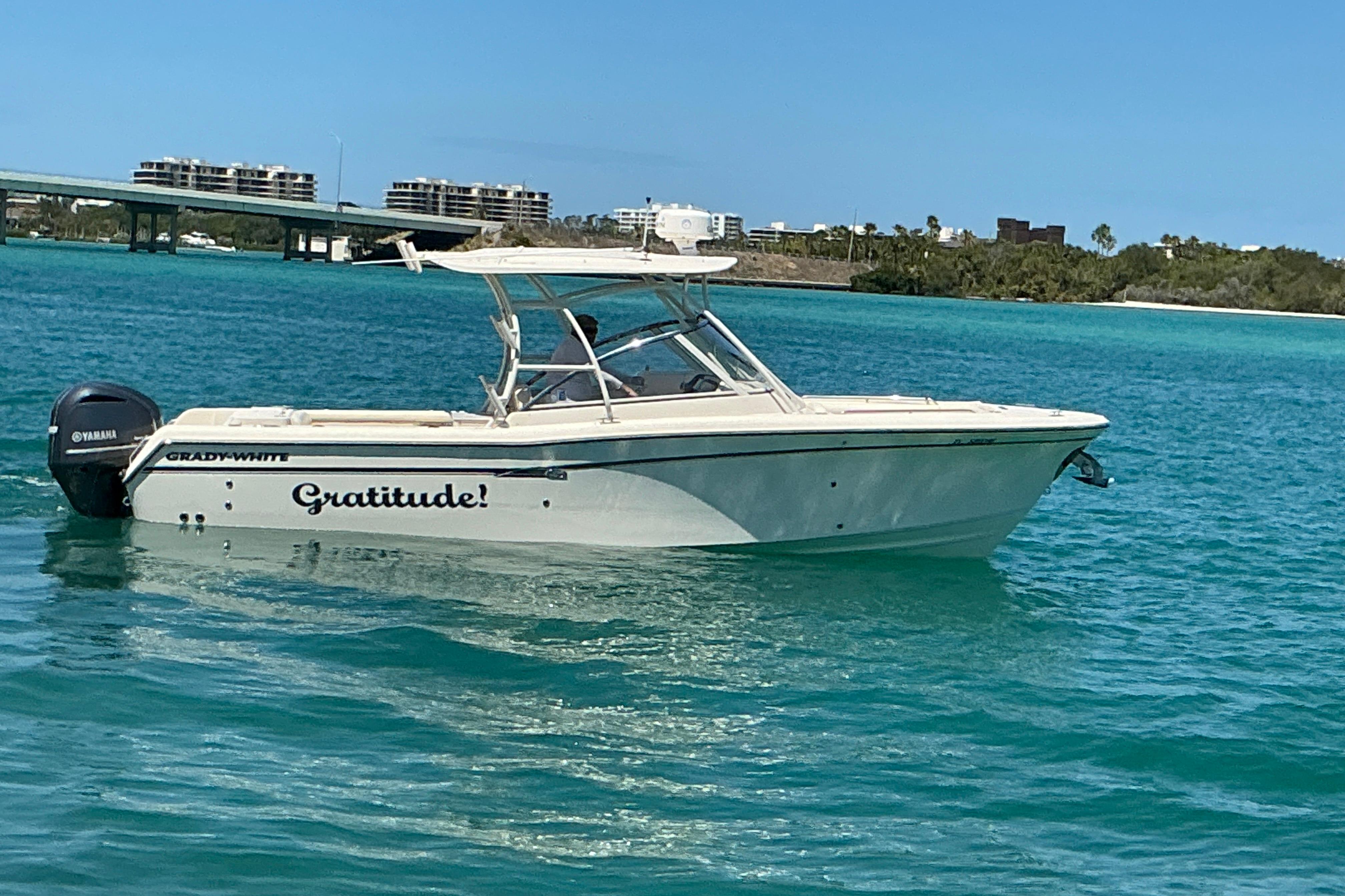 2018 Grady-White Freedom 285 boat named "Gratitude" on turquoise water near a bridge.