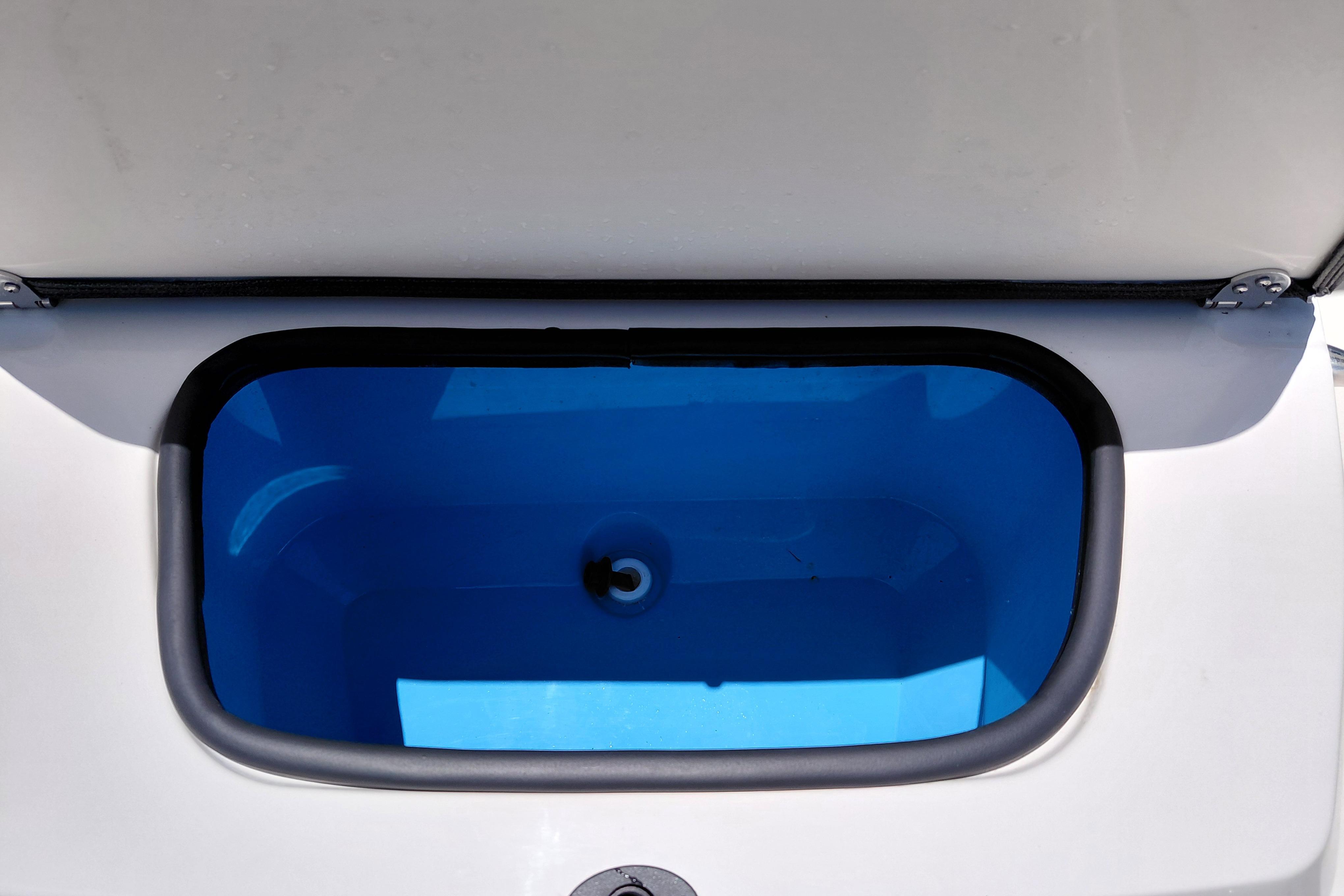 Open storage compartment in 2023 Stingray 206 CC boat, featuring a blue interior.