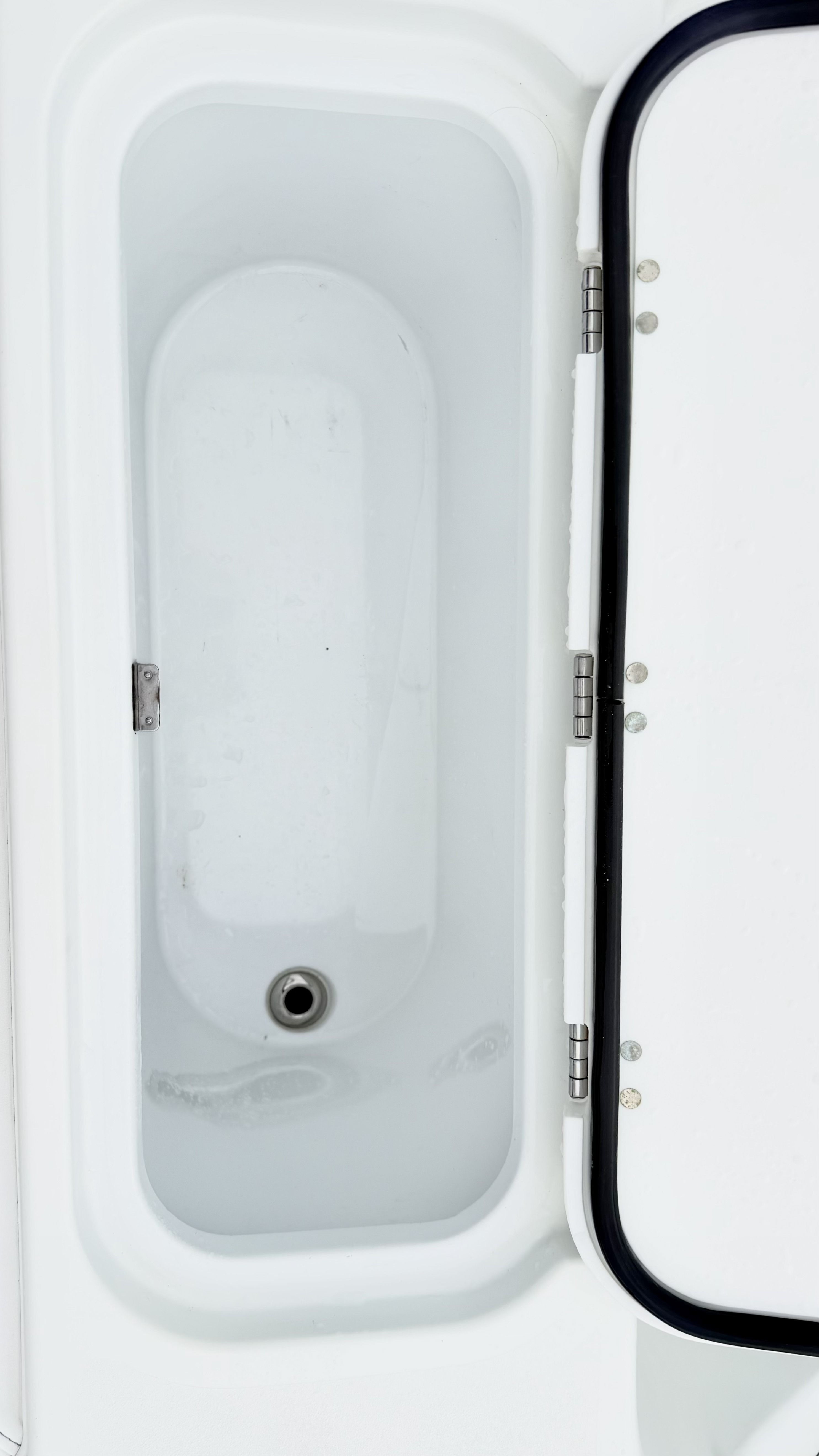 An open storage compartment on a boat with a drain at the bottom.