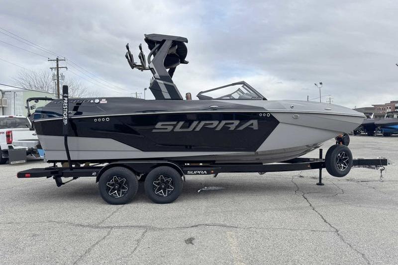 2026 Supra SA boat on trailer, sleek design, black and gray color scheme.