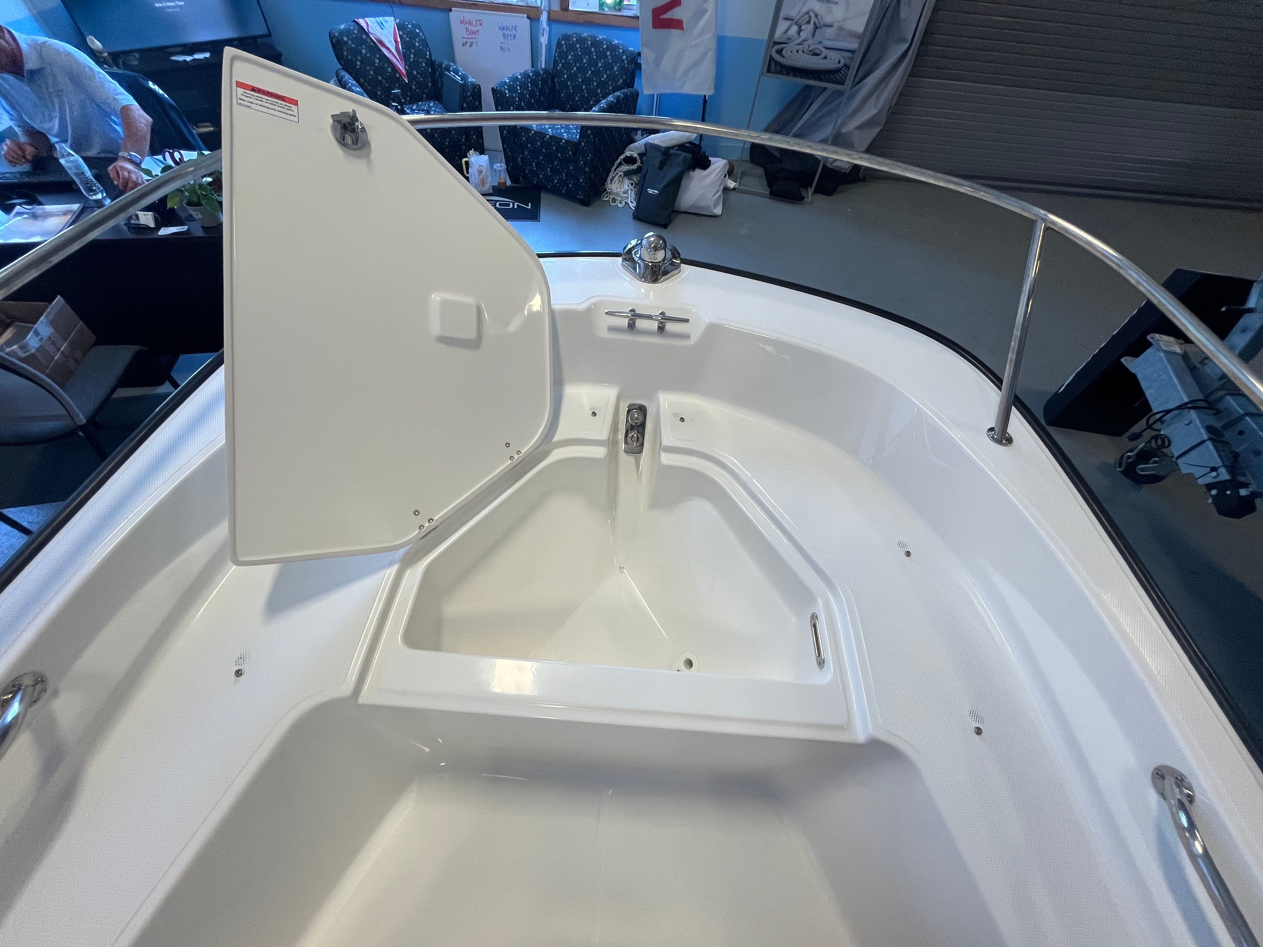 The image shows the bow area of a Boston Whaler 150 Montauk with an open storage compartment.