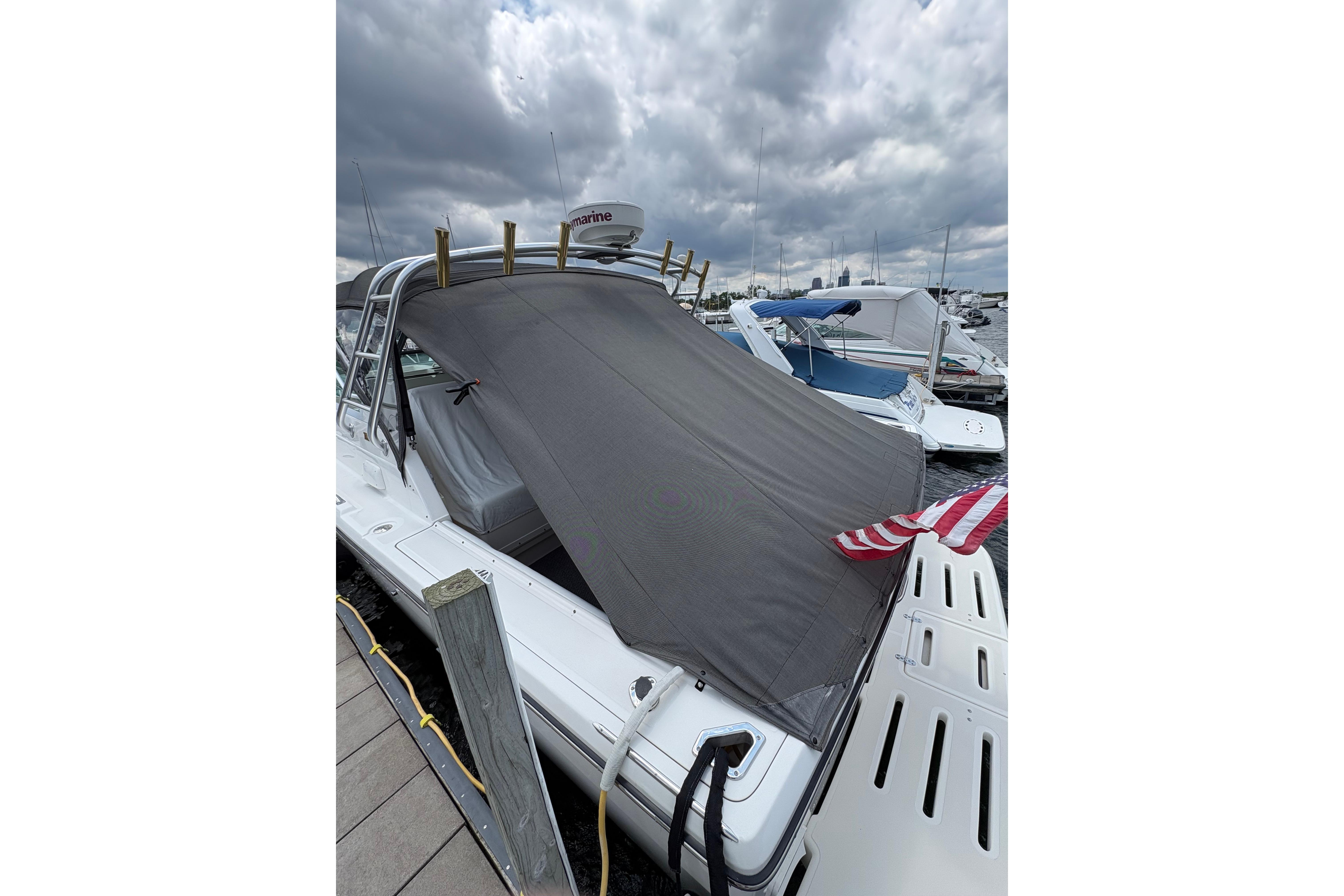 1999 Tiara Yachts 3100 Open docked, covered with a tarp under cloudy skies.