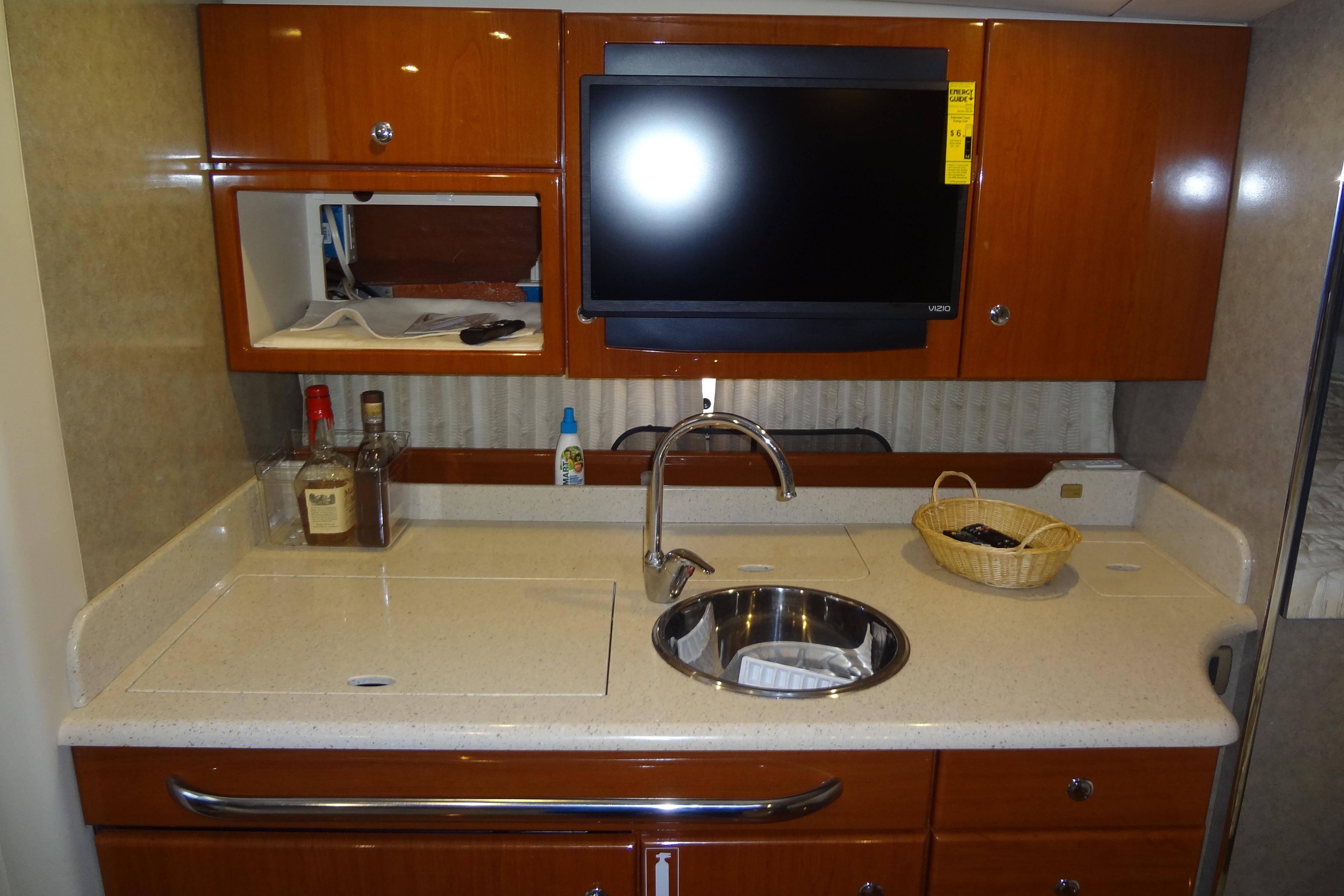 2007 Formula 34 Performance Cruiser kitchen with sink, TV, and wooden cabinets.