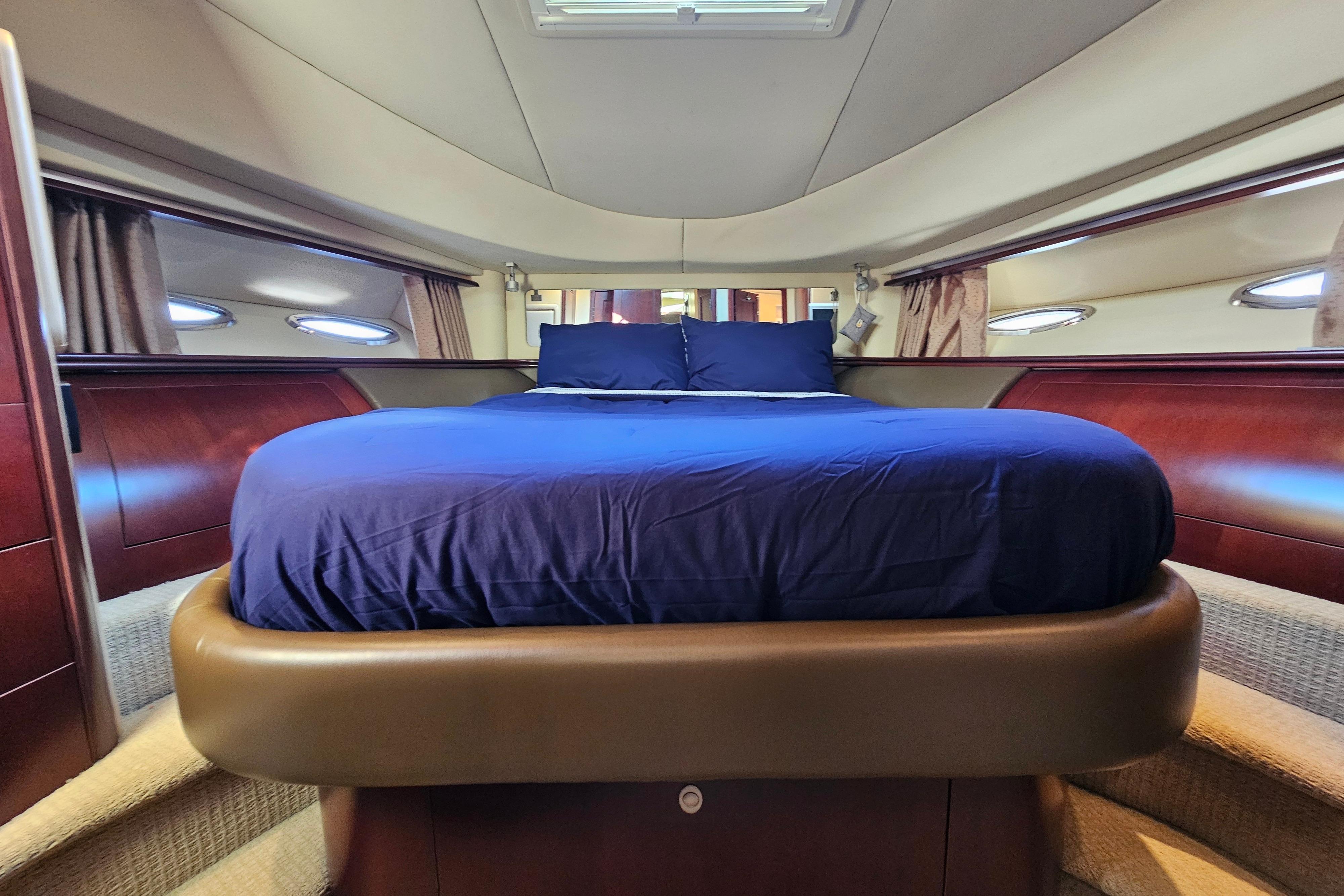 Luxurious bedroom interior of 2006 Sea Ray 580 Sedan Bridge yacht with elegant wood finishes.