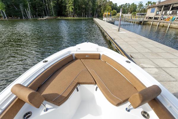 2025 Sea Hunt Ultra 235 SE boat with brown seating, docked by a serene lake.