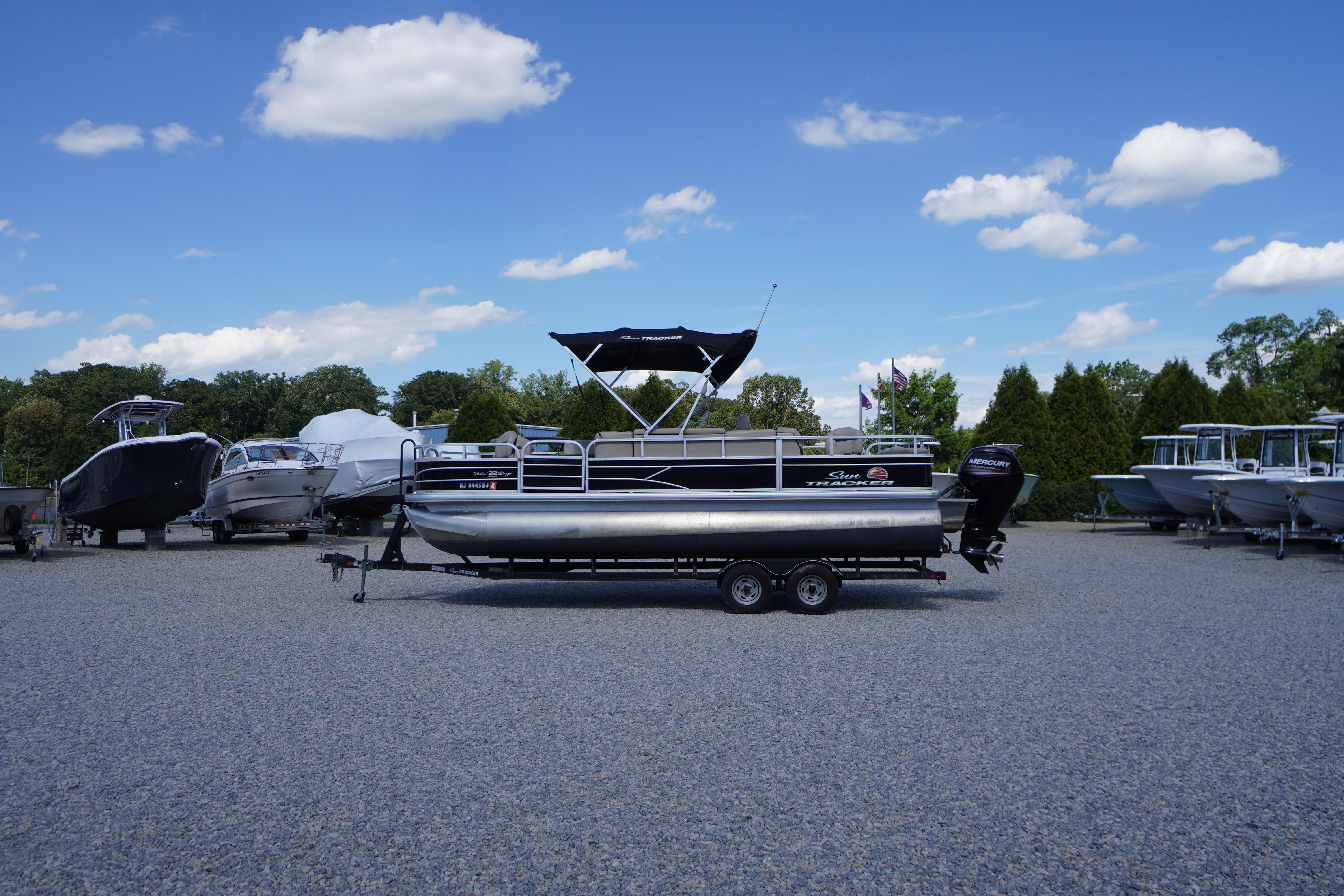 2019 SUNTRACKER Fishin' Barge 22 DLX pontoon boat on trailer, parked outdoors.