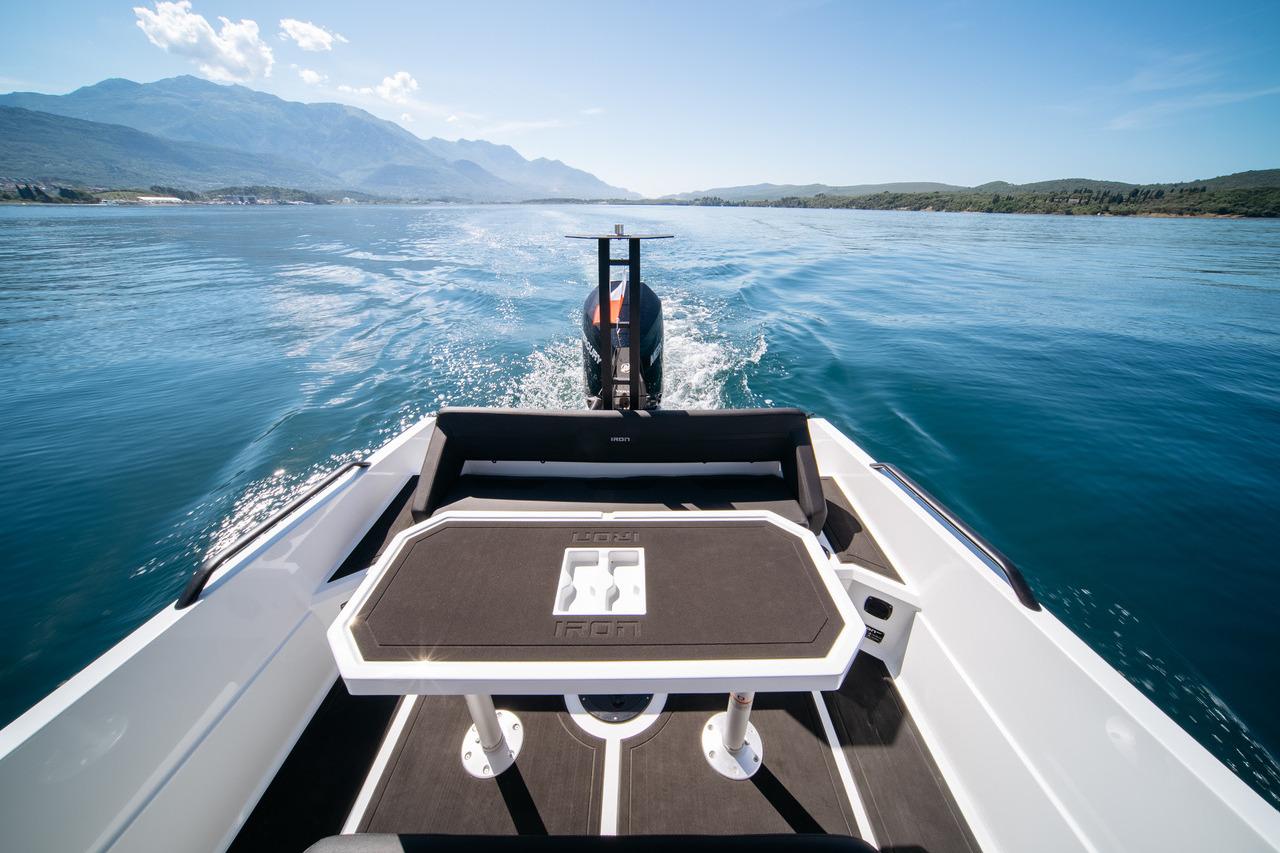 Custom 827 boat cruising on a serene lake, 2024 model, with scenic mountain backdrop.
